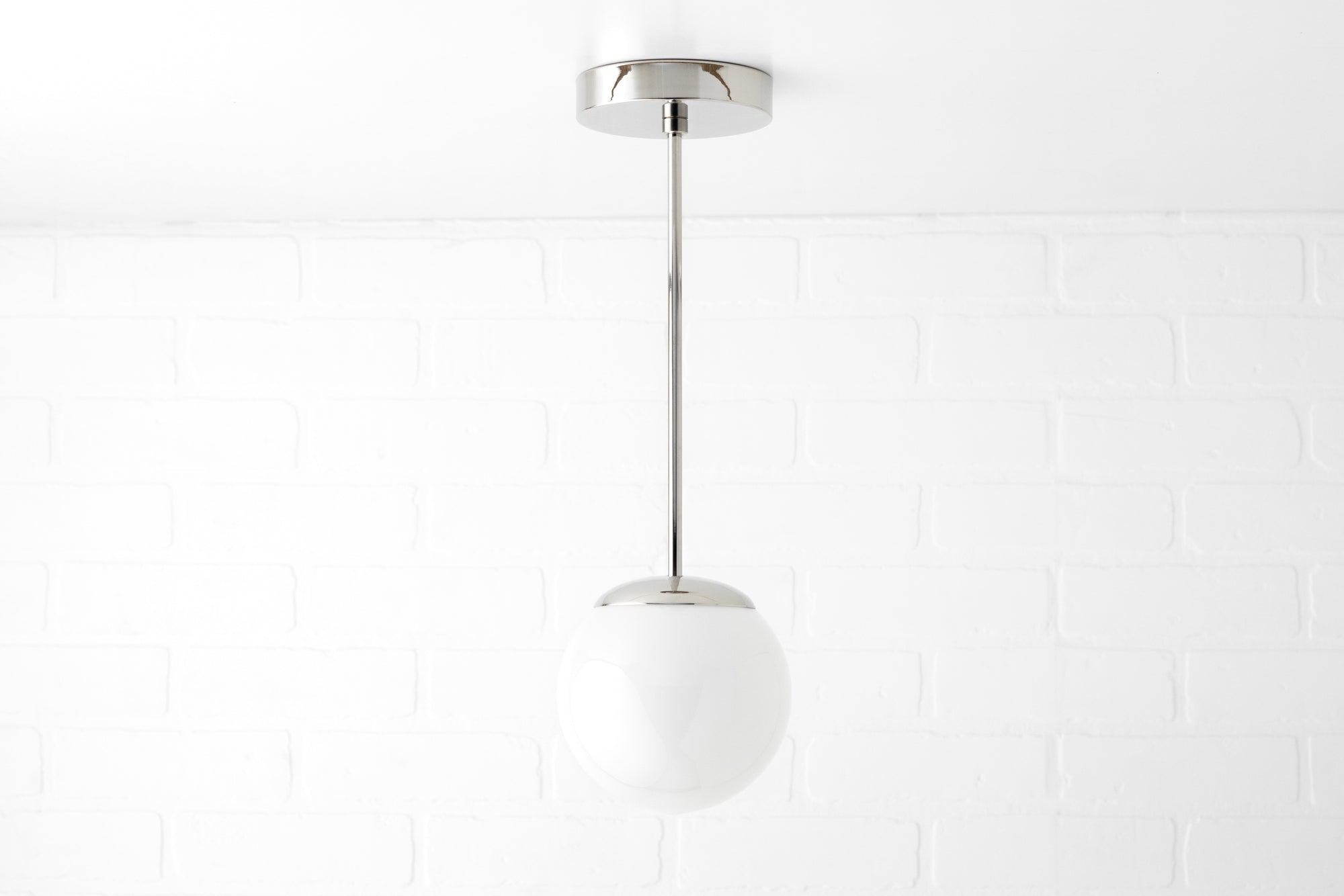 Mid-century modern pendant light with a white glass globe and chrome fixture suspended by a slim rod. - PENDANT MODEL NO. 7056