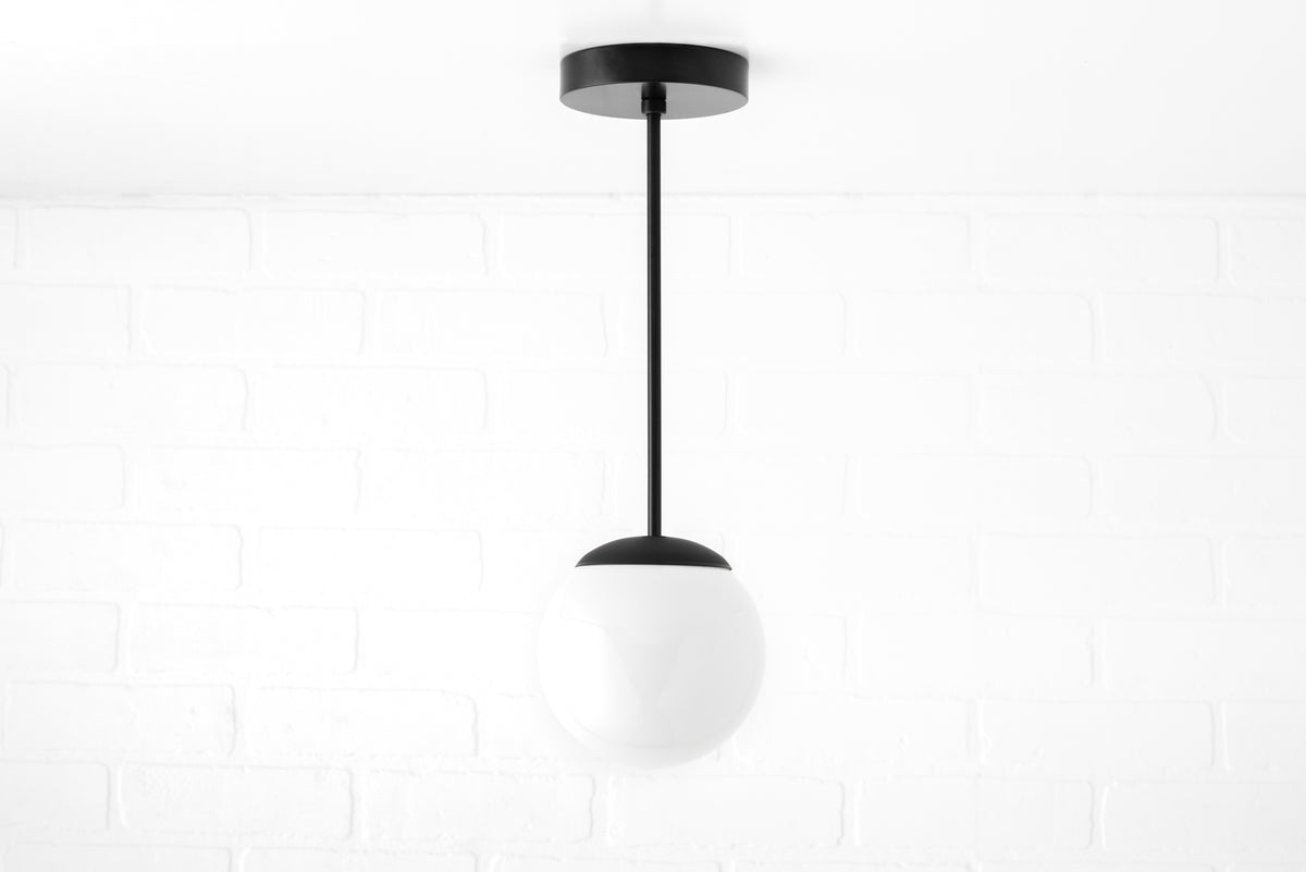 Mid-century modern pendant light with a black metal fixture and a white frosted glass globe shade. - PENDANT MODEL NO. 7056