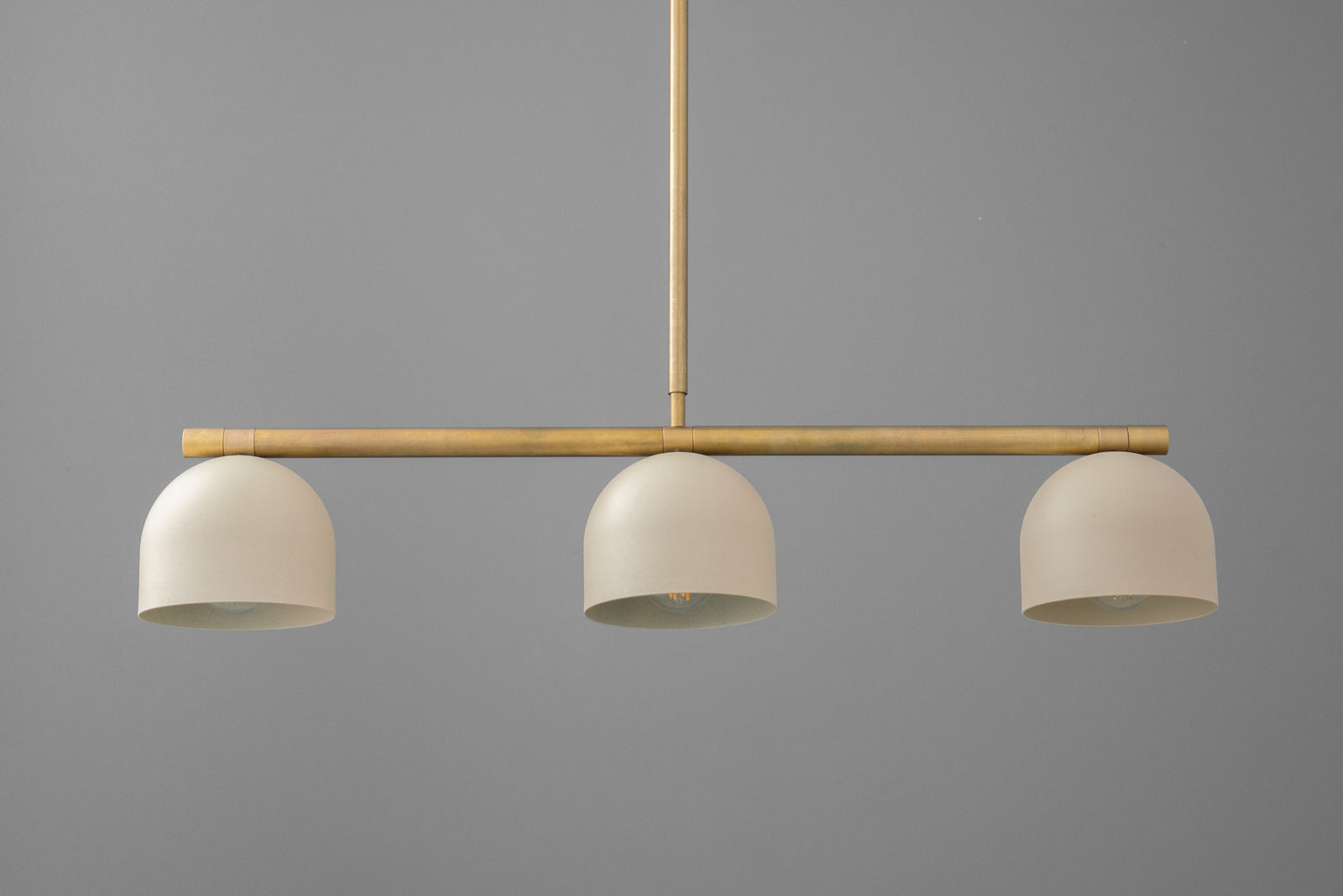 Modern gold-toned chandelier with three smooth, matte white dome shades and a horizontal bar design. - CHANDELIER MODEL NO. 8477