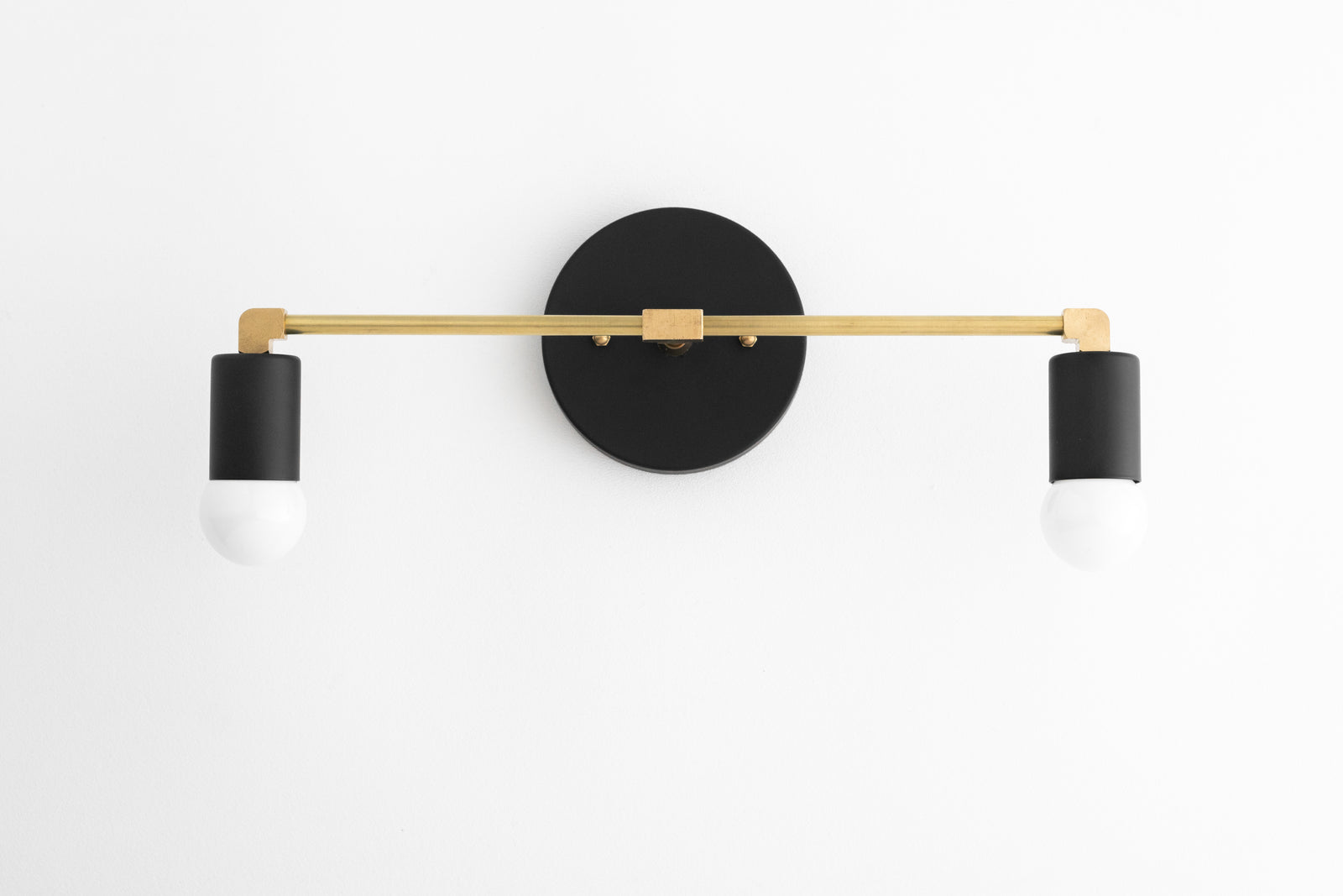 Two-light vanity light in Black/R. Brass/Black, with a Black wall plate and sockets on a Raw Brass bar. - VANITY LIGHT MODEL NO. 8412