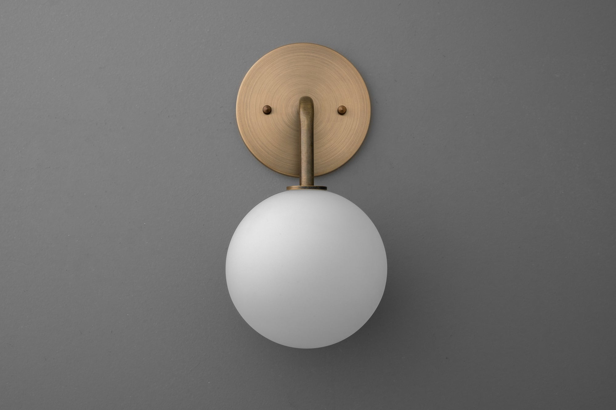Minimalist wall sconce with matte antique brass finish and frosted white globe shade. - SCONCE MODEL NO. 7660
