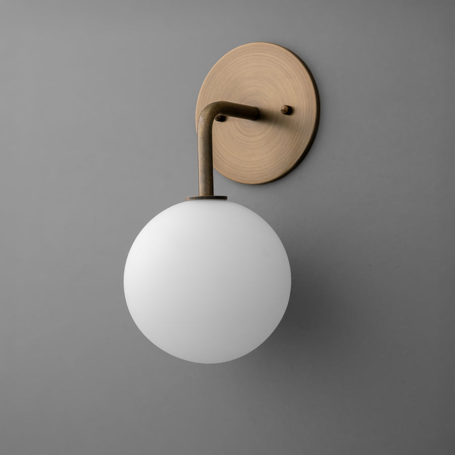 Minimal wall sconce with matte white glass globe and antique brass round backplate and arm. - SCONCE MODEL NO. 7660