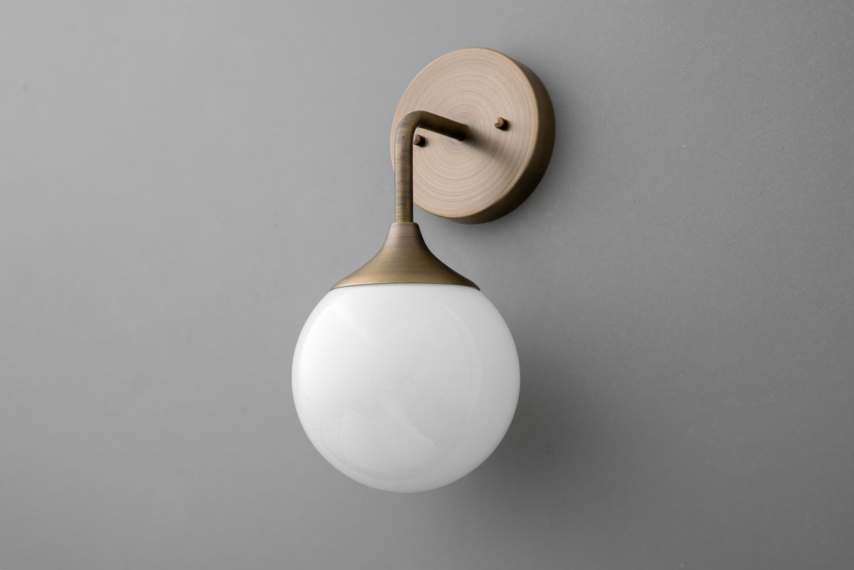 Antique brass wall sconce with round white glass globe shade on gray background. - SCONCE MODEL NO. 1752