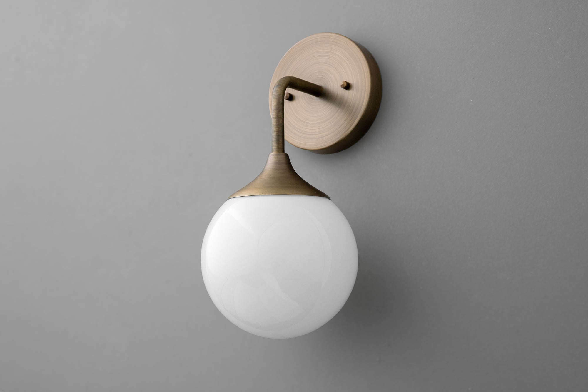 Antique brass wall sconce with round white glass globe shade on gray background. - SCONCE MODEL NO. 1752