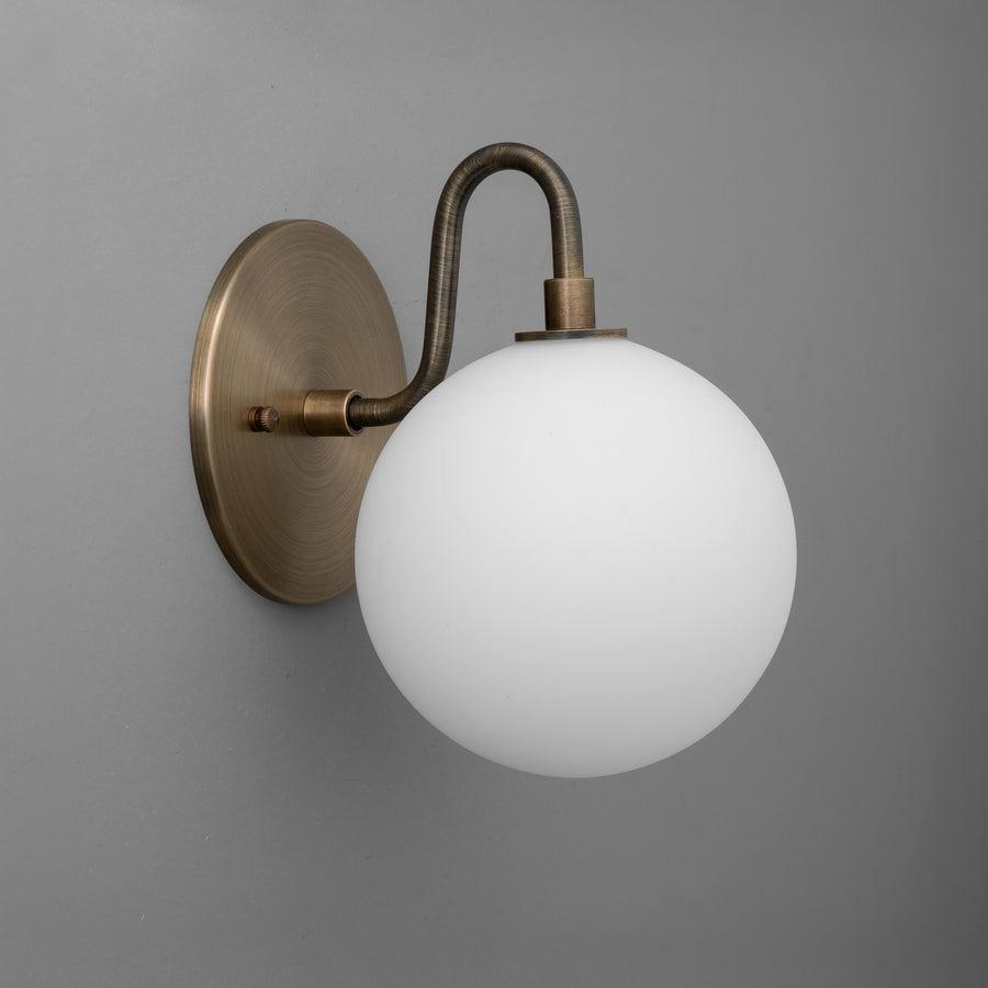 Wall sconce with antique brass finish and frosted white globe shade mounted on curved arm. - SCONCE MODEL NO. 8637