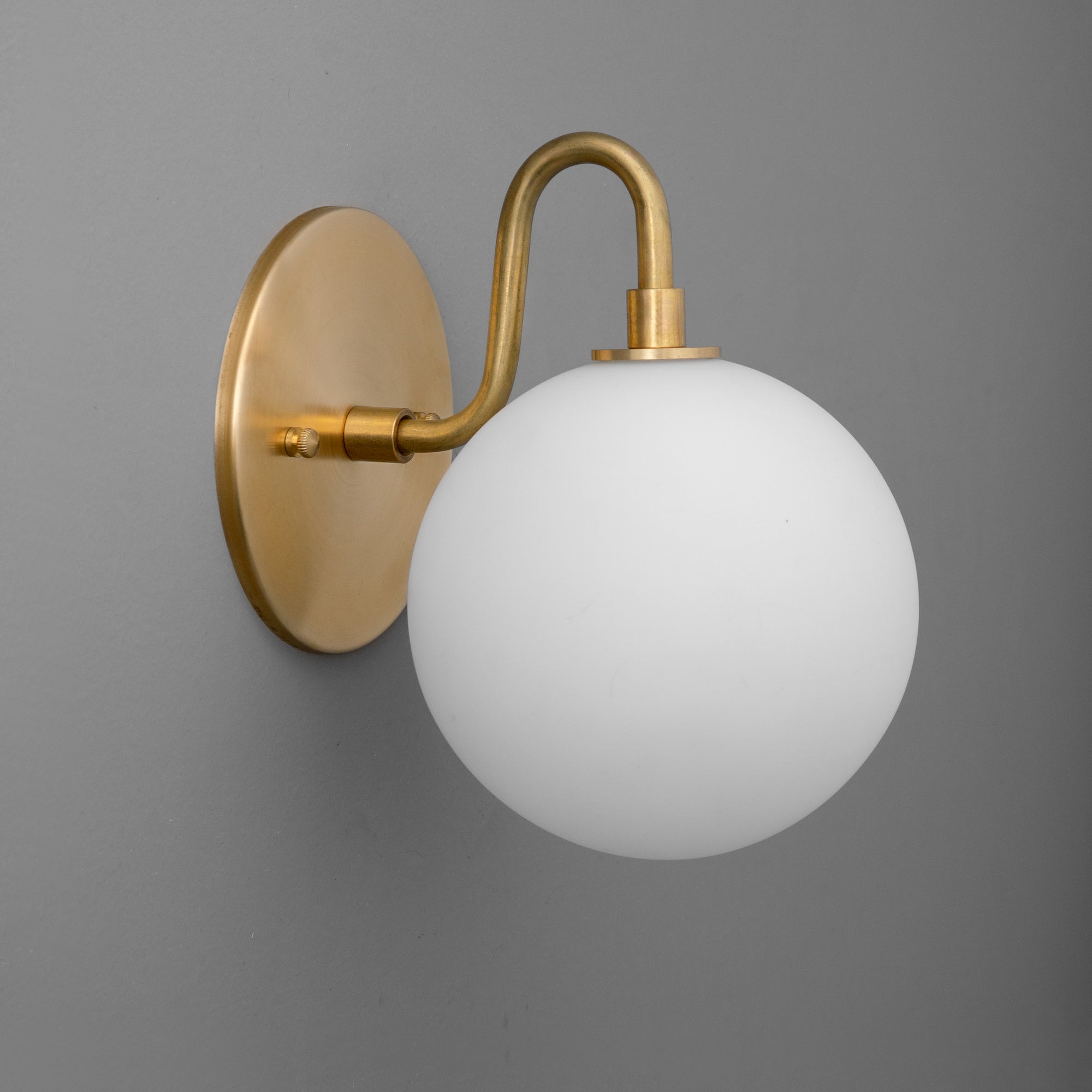 Wall sconce with round frosted glass globe and curved antique brass arm and base. - SCONCE MODEL NO. 8637