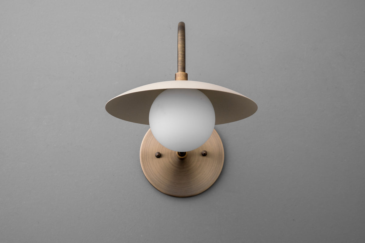 Antique brass wall sconce with cream dome shade and frosted globe bulb on gray background. - SCONCE MODEL NO. 3799