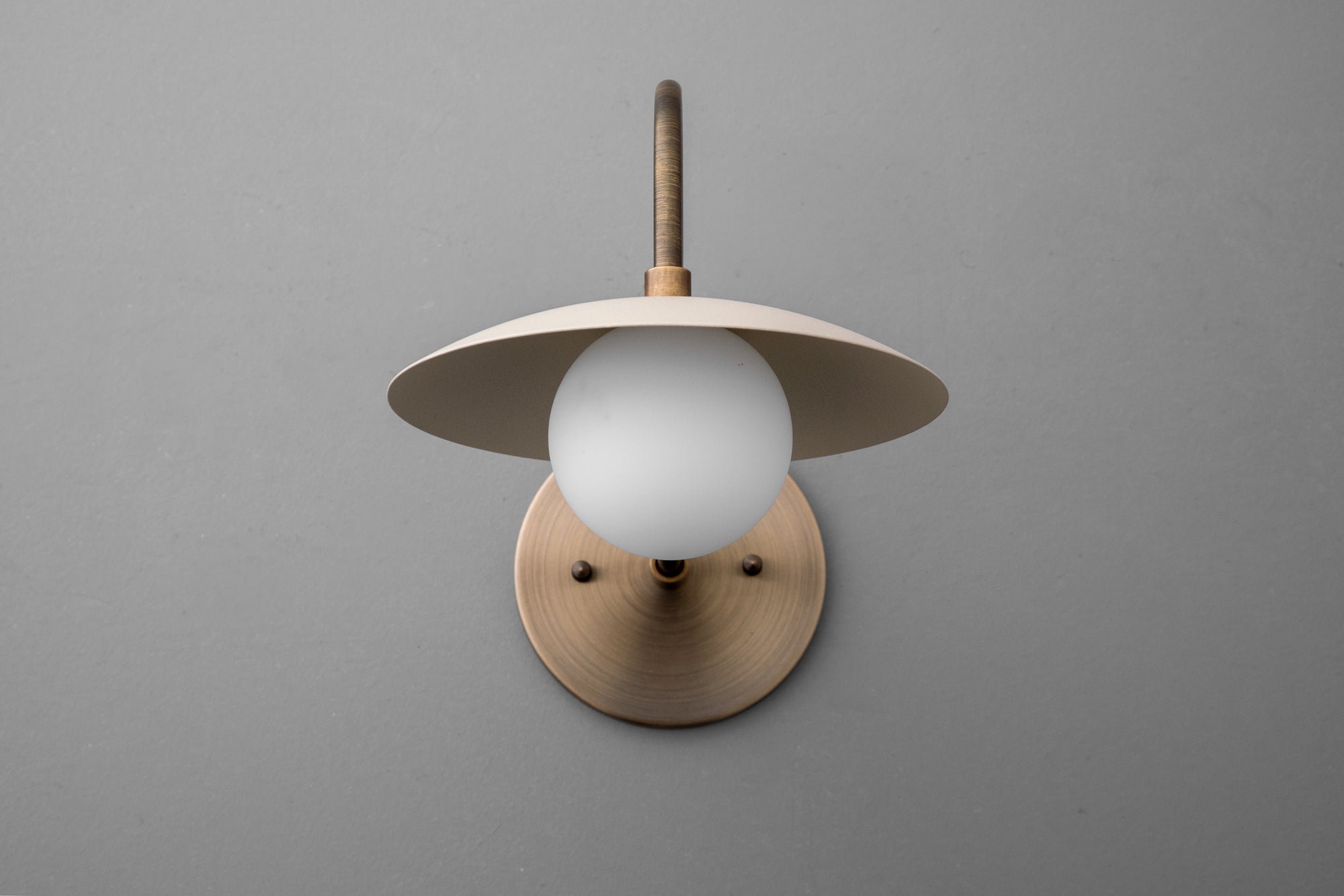 Antique brass wall sconce with cream dome shade and frosted globe bulb on gray background. - SCONCE MODEL NO. 3799