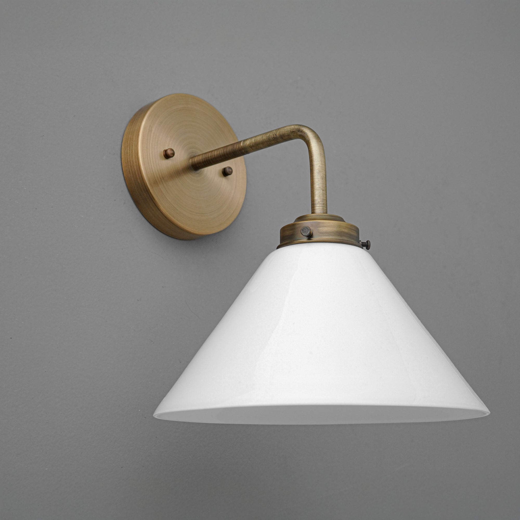Wall sconce with antique brass arm and round base, featuring a white conical shade. - SCONCE MODEL NO. 8751