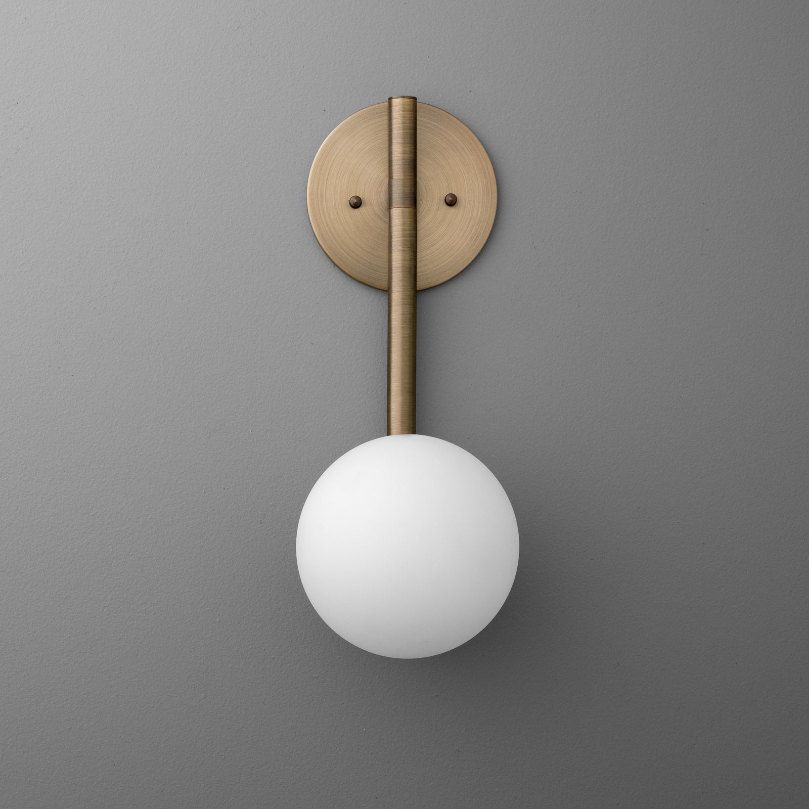 Minimalist wall sconce with antique brass finish, vertical rod, and frosted globe shade. - SCONCE MODEL NO. 0981