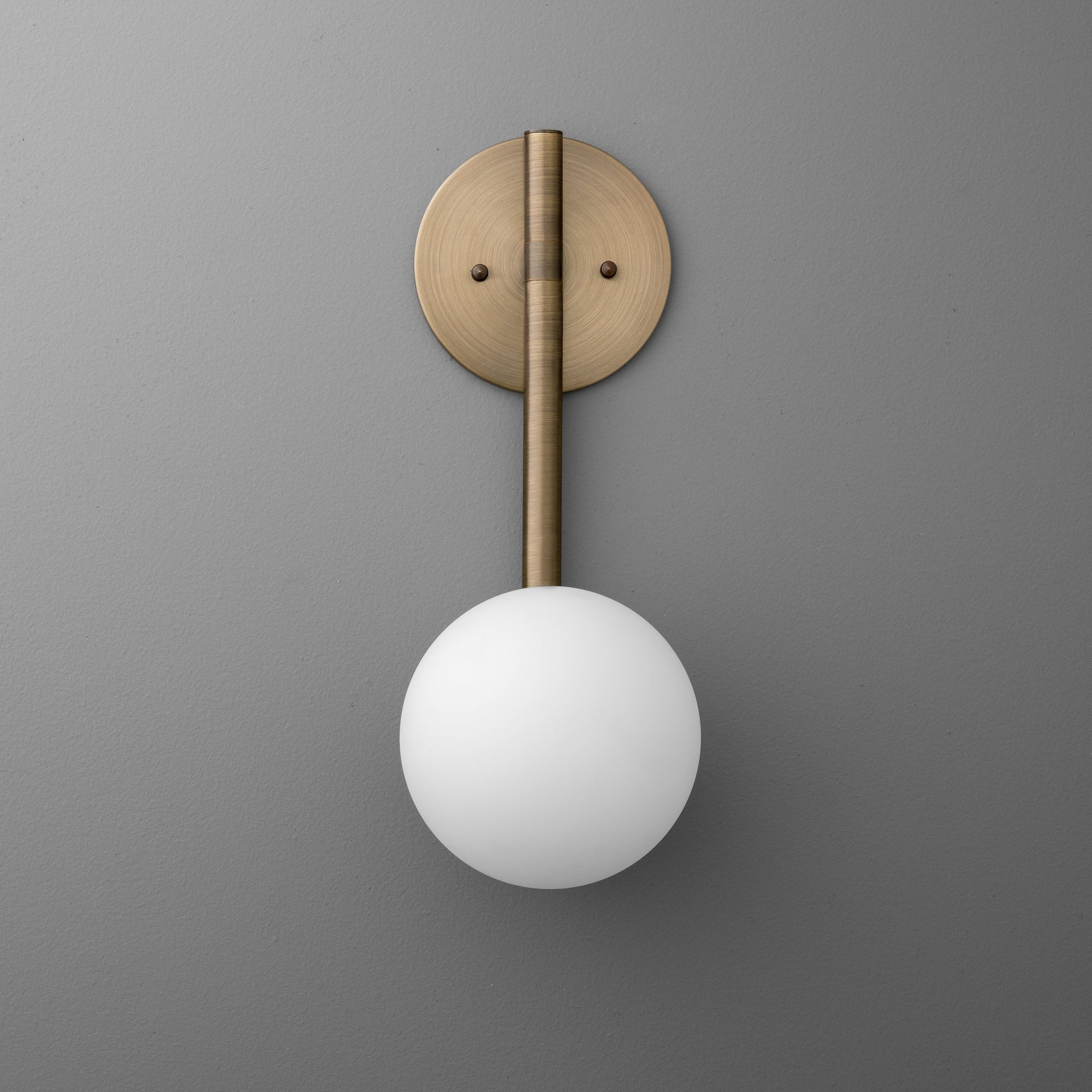 Minimalist wall sconce with antique brass finish, vertical rod, and frosted globe shade. - SCONCE MODEL NO. 0981