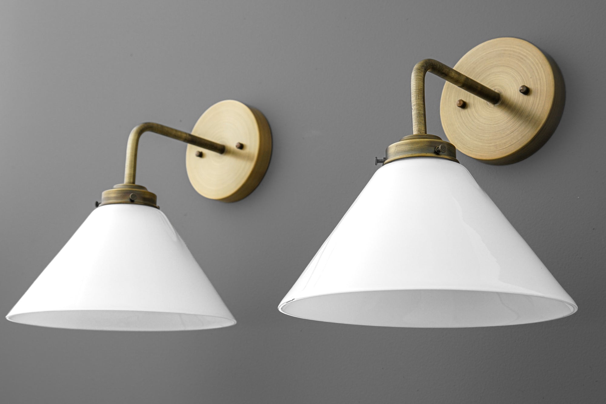 Pair of wall sconces with matte white conical shades and antique brass curved arms and round backplates. - SCONCE MODEL NO. 8751