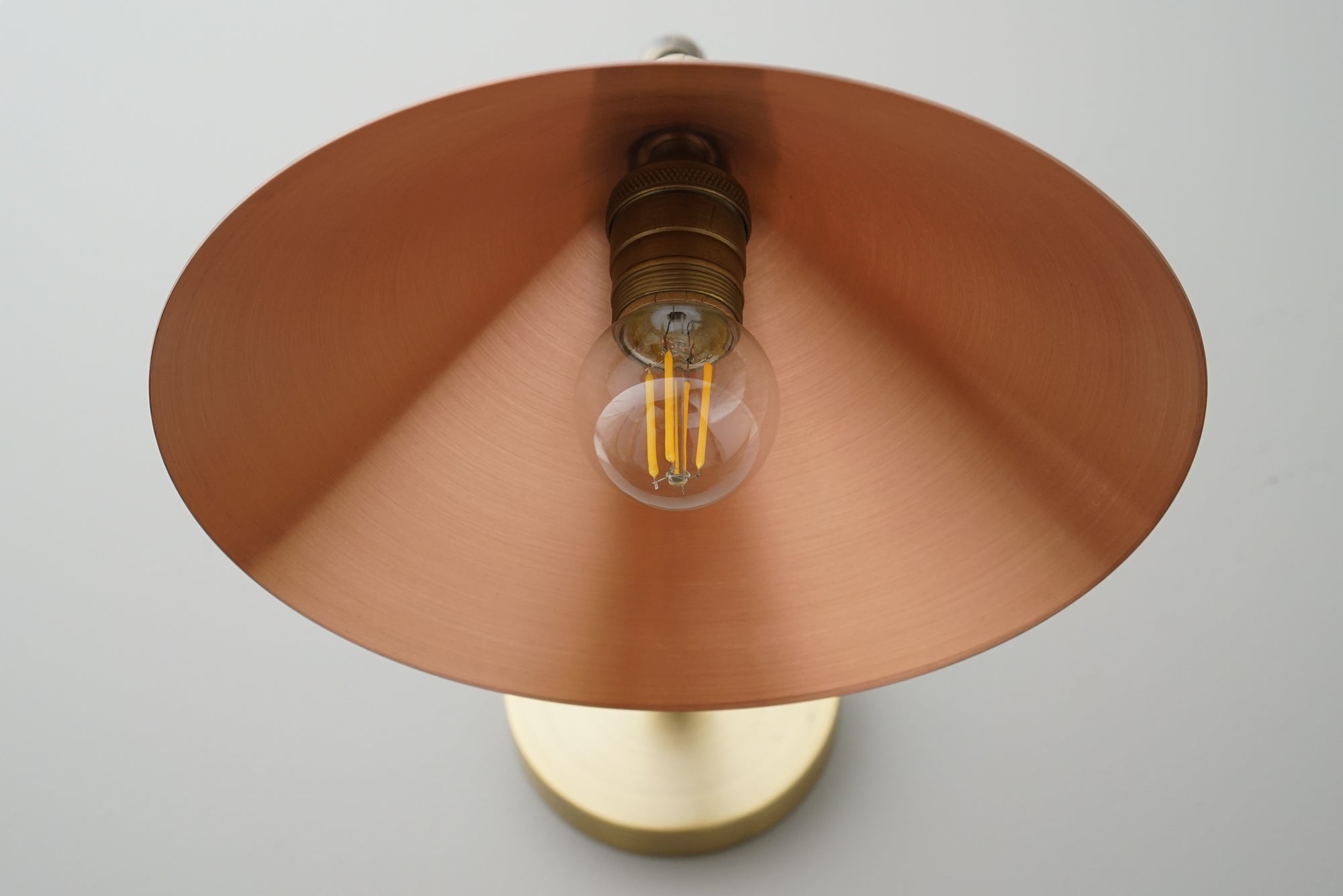 Wall sconce with wide conical copper shade and exposed Edison bulb on brass base. - SCONCE MODEL NO. 7574