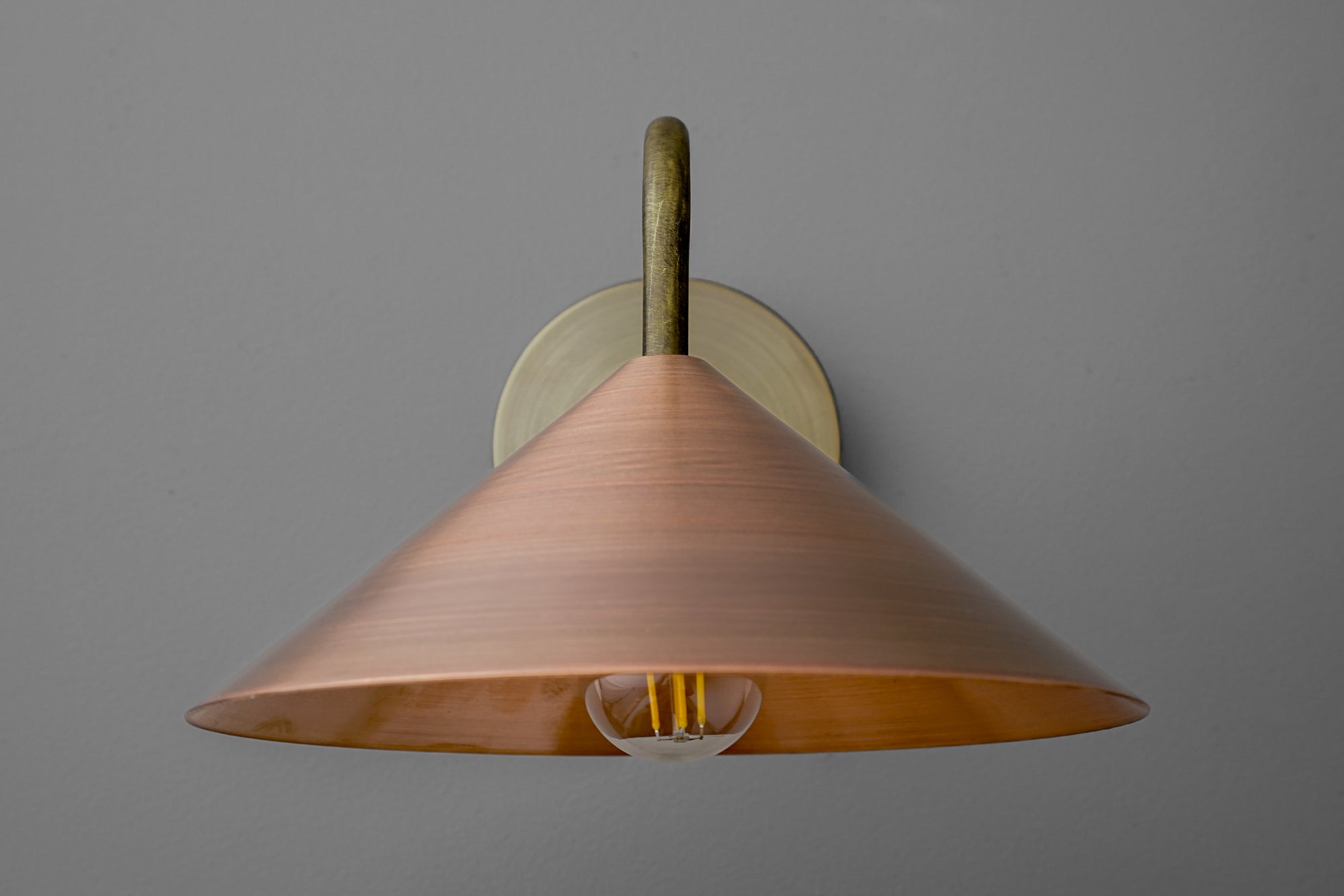 Wall sconce with wide conical copper shade and antique brass mounting on gray background. - SCONCE MODEL NO. 7574