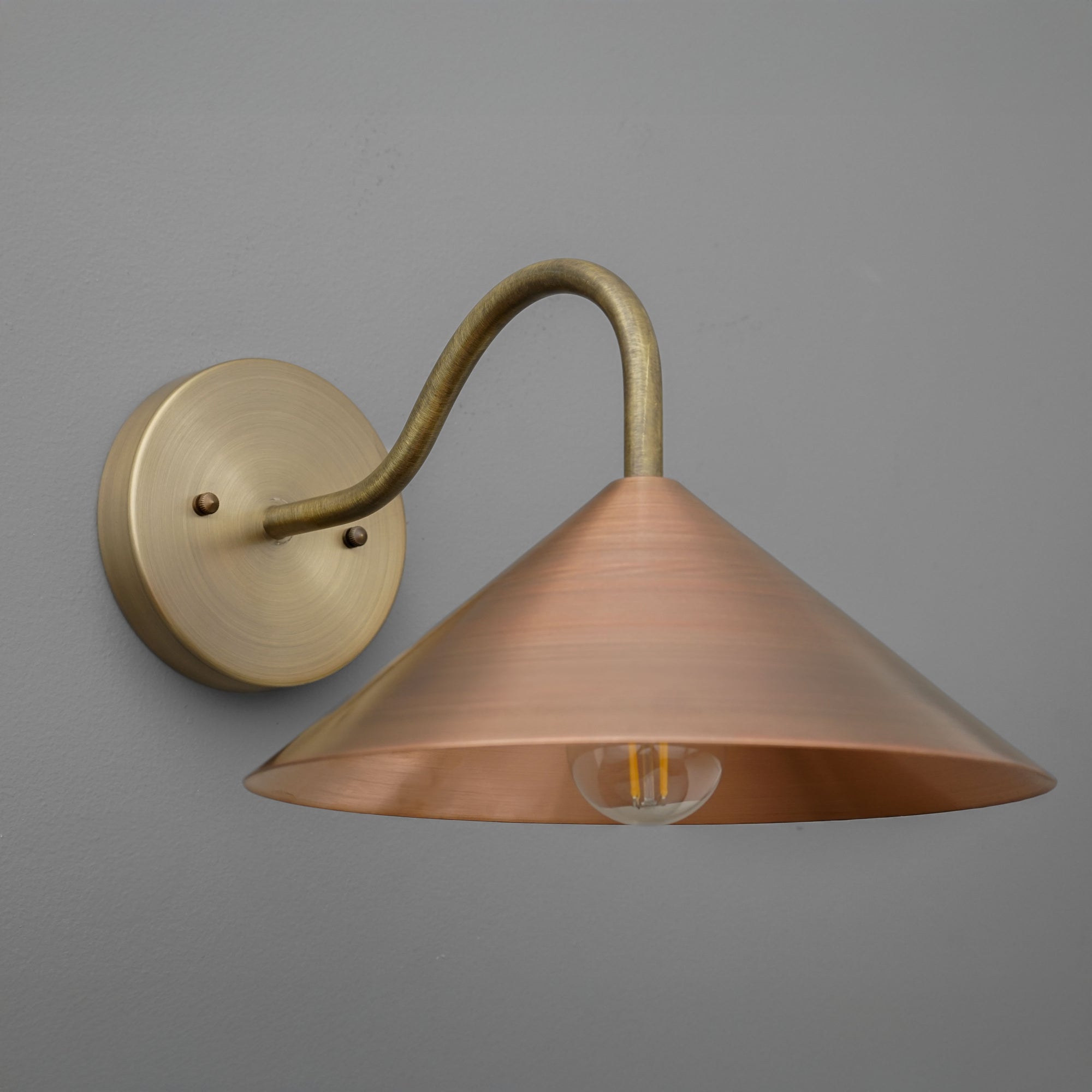 Wall sconce with wide conical copper shade and antique brass curved arm mounted on round brass base. - SCONCE MODEL NO. 7574