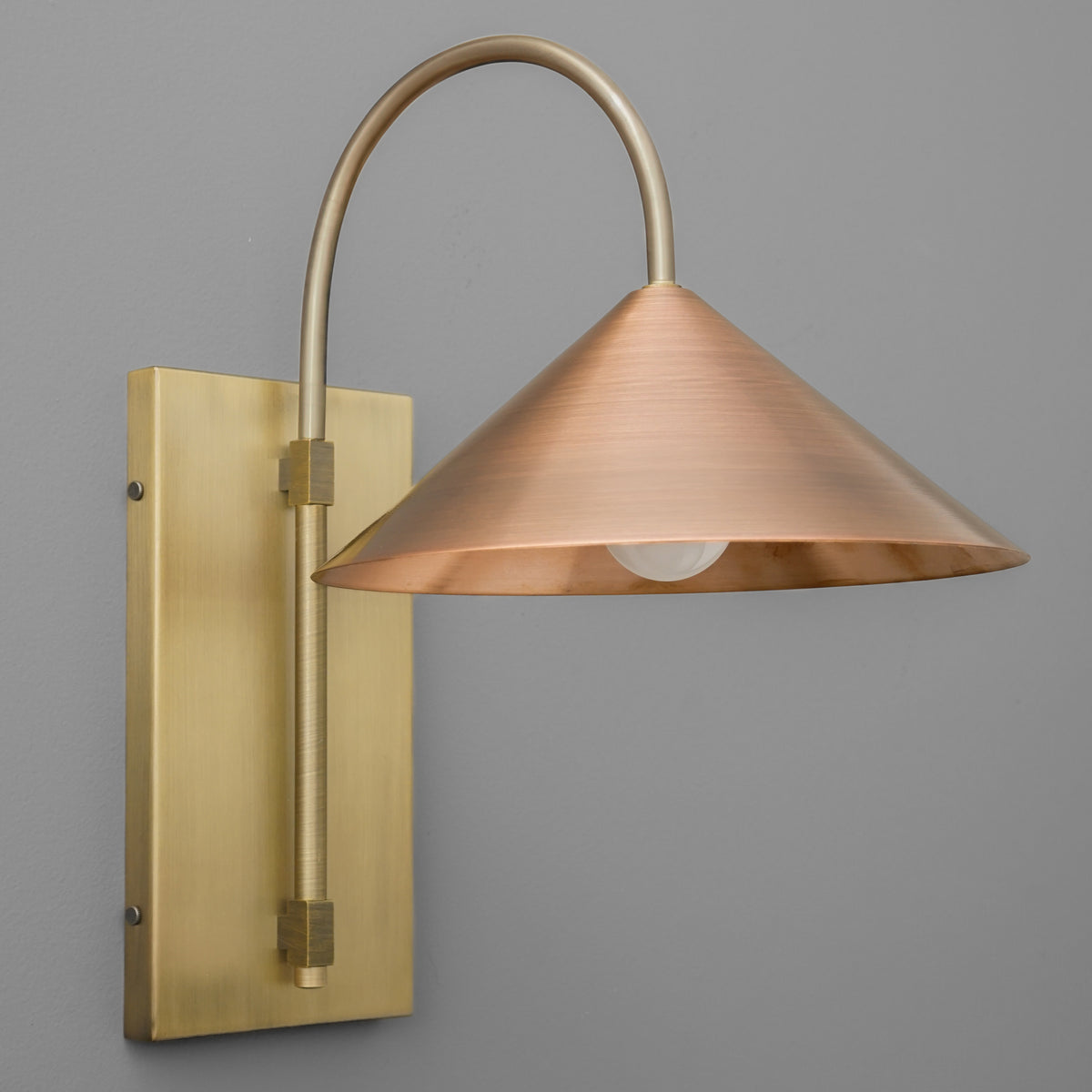 Wall sconce with raw brass rectangular backplate and curved arm, copper cone-shaped shade. - SCONCE MODEL NO. 2096