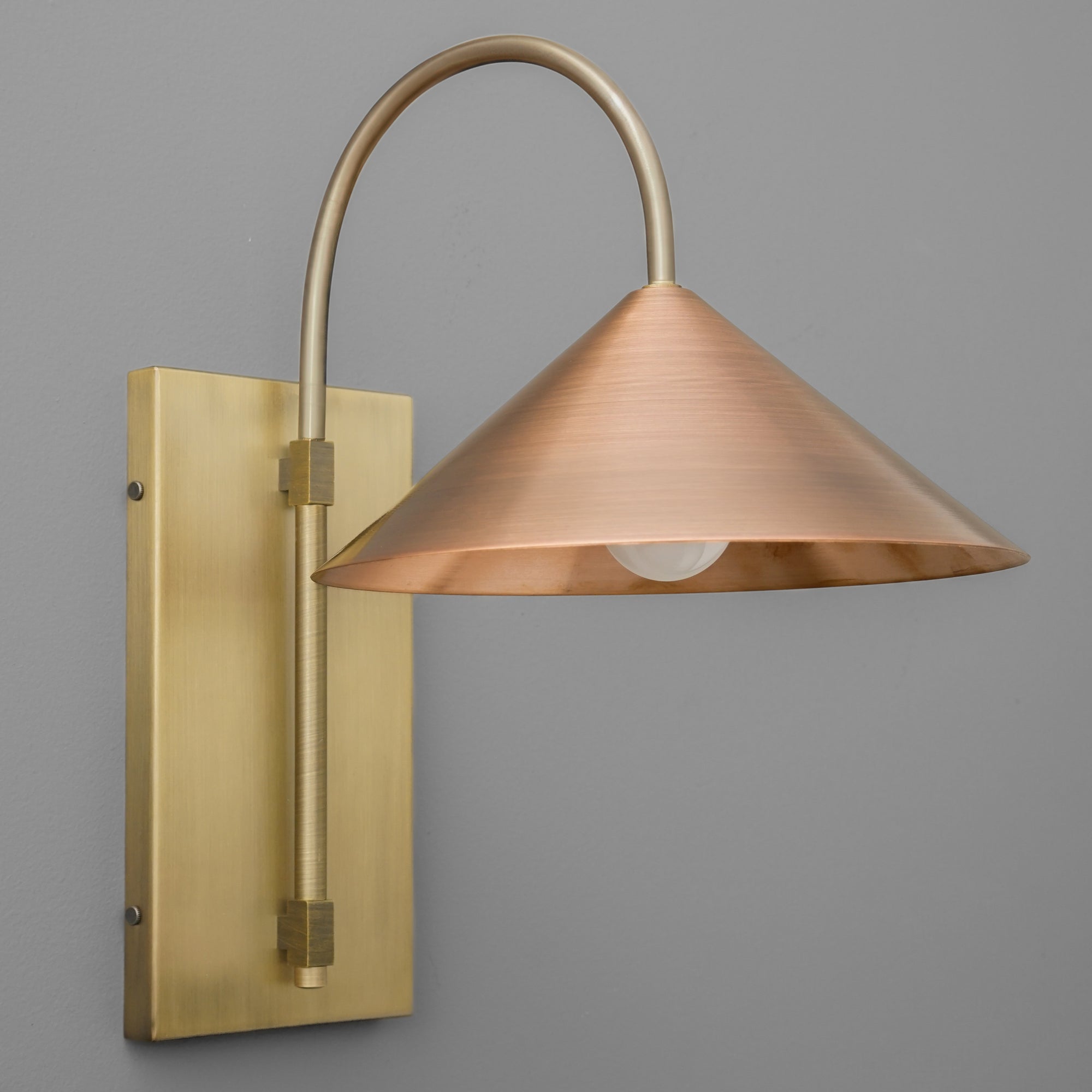 Wall sconce with raw brass rectangular backplate and curved arm, copper cone-shaped shade. - SCONCE MODEL NO. 2096
