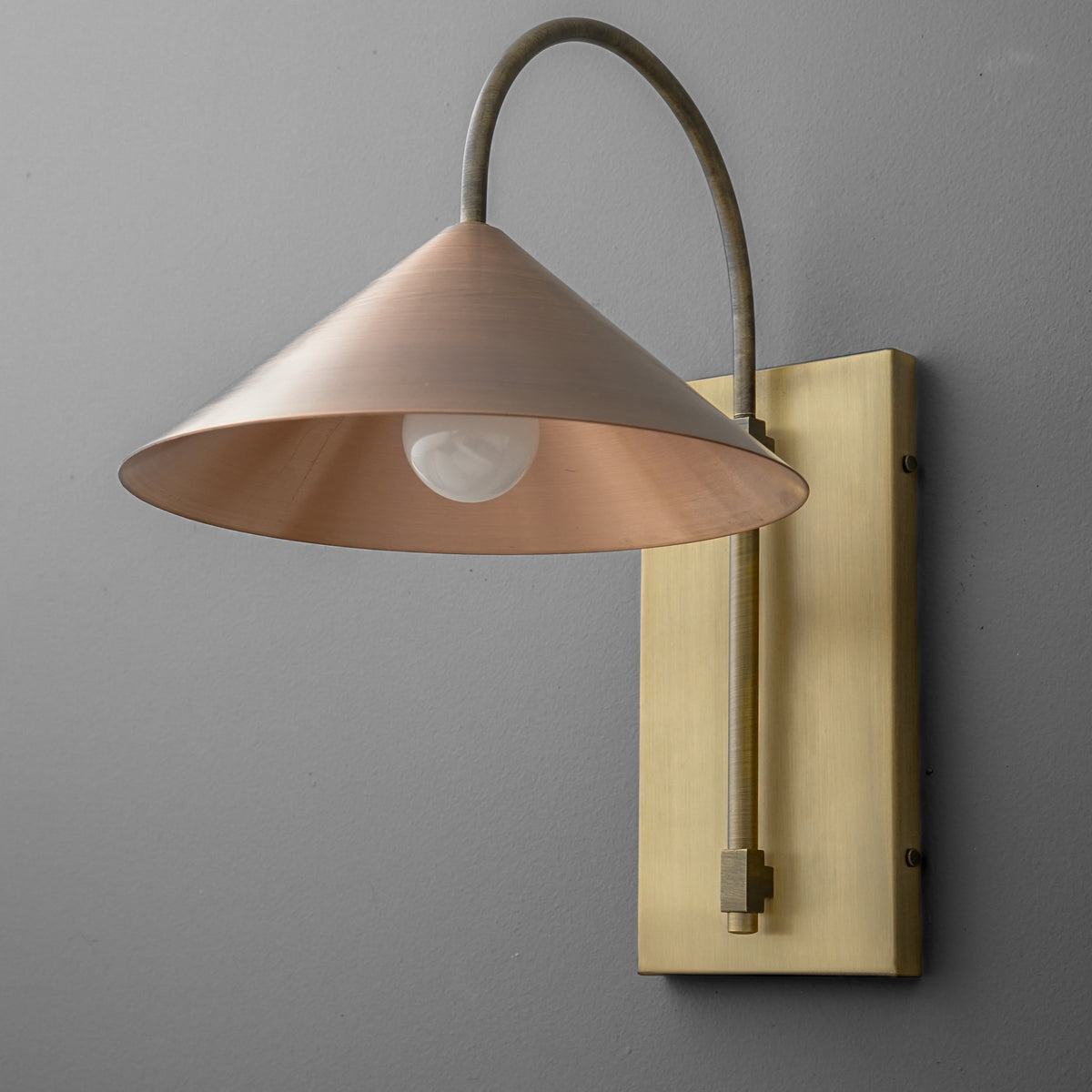 Wall sconce with conical copper shade and curved brass arm mounted on rectangular brass backplate. - SCONCE MODEL NO. 2096