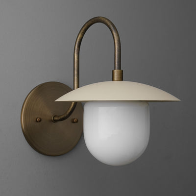 Antique brass sconce with curved arm and wide cream metal shade over frosted white glass globe diffuser. - SCONCE MODEL NO. 7191
