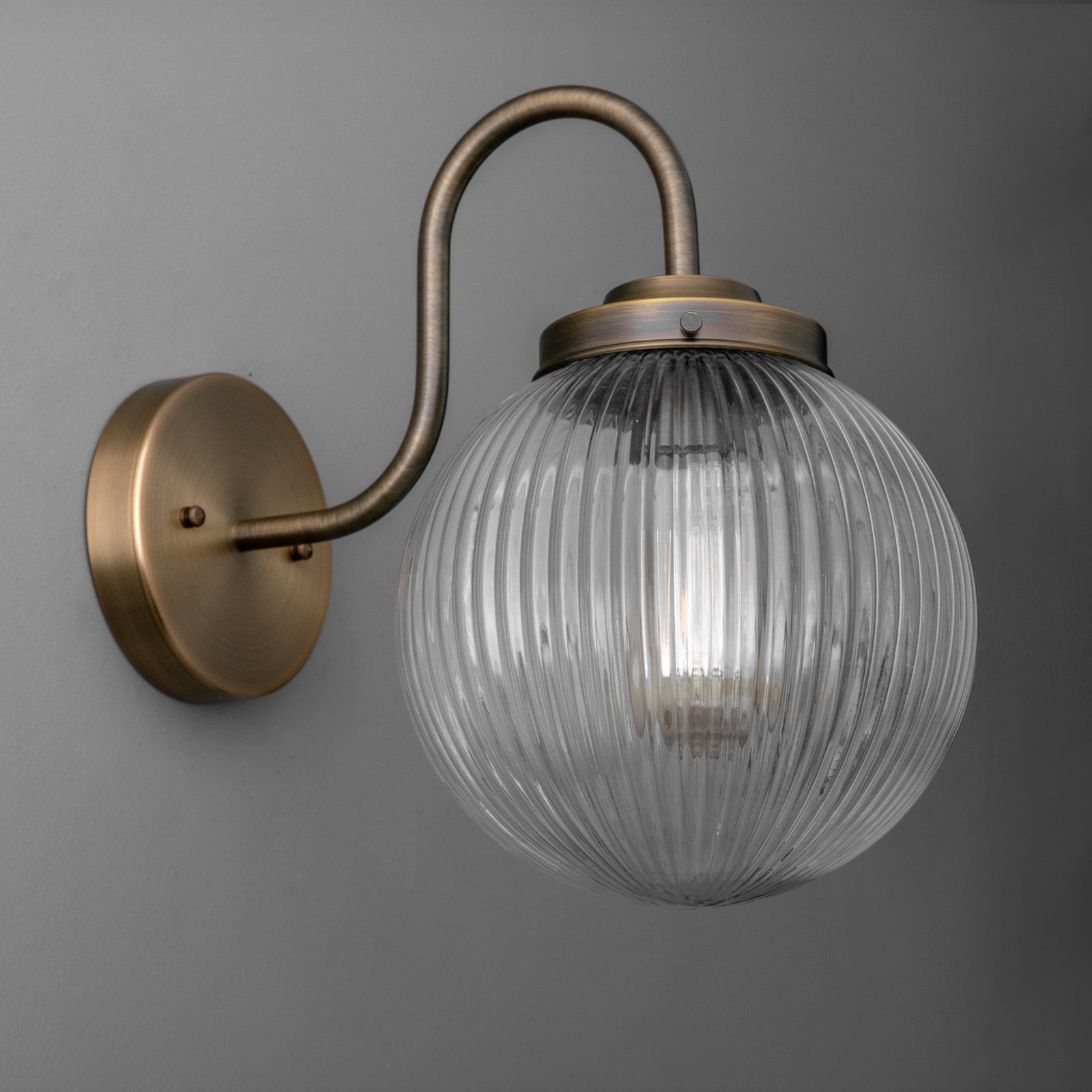Wall-mounted bronze sconce with ribbed clear glass globe shade and curved arm design. - SCONCE MODEL NO. 1009