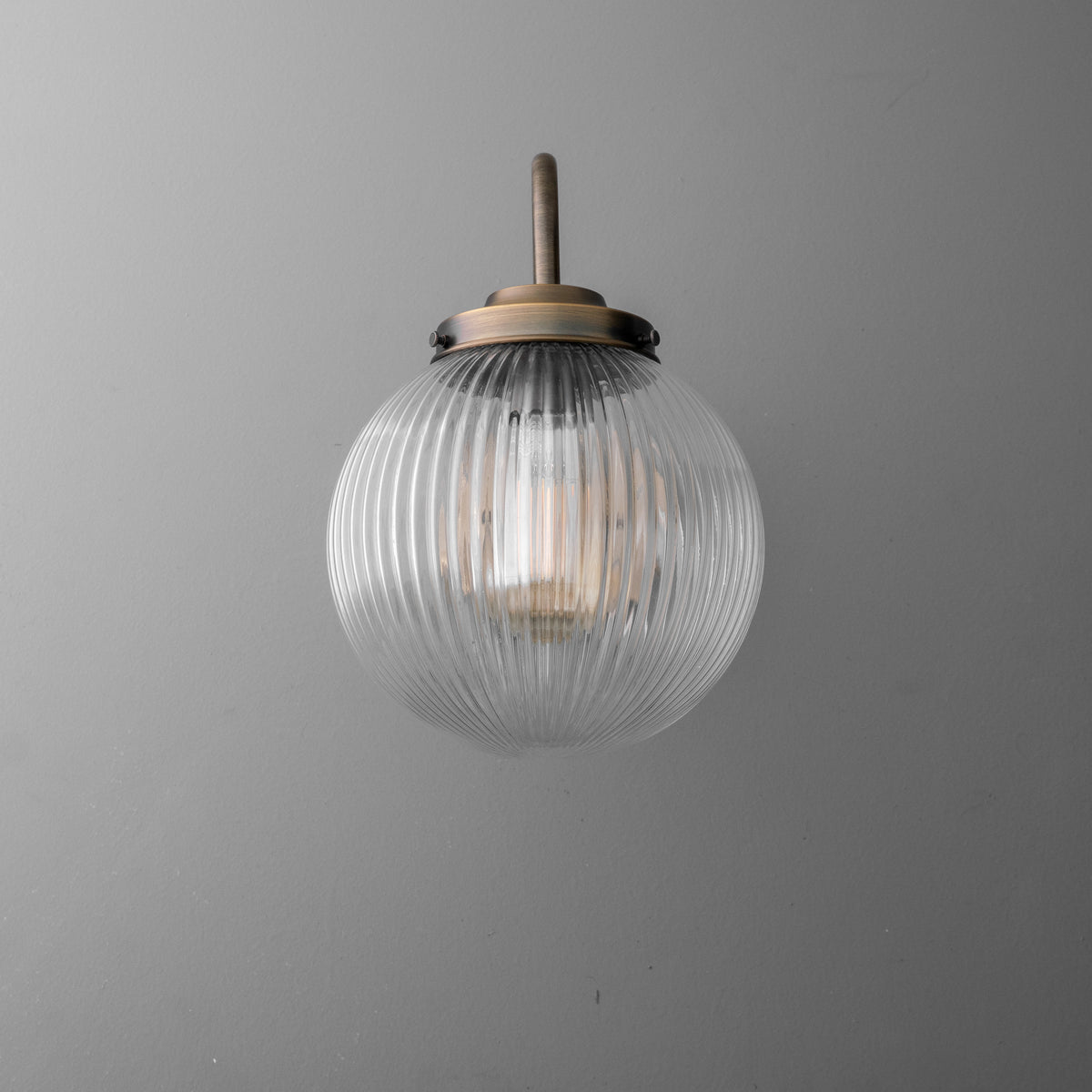 Clear ribbed glass globe sconce with bronze metal fixture and single exposed bulb. - SCONCE MODEL NO. 1009