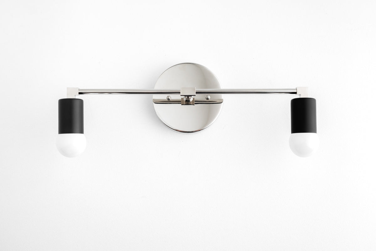 Two-light vanity light in Polished Nickel/Black, with a Polished Nickel wall plate and bar and Black sockets. - VANITY LIGHT MODEL NO. 8412