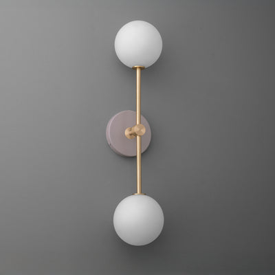 Wall sconce with raw brass finish, mauve circular backplate, and two white frosted glass globes. - SCONCE MODEL NO. 9776