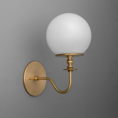 Wall sconce with antique brass finish, curved arm, and frosted white glass globe shade. - SCONCE MODEL NO. 7857