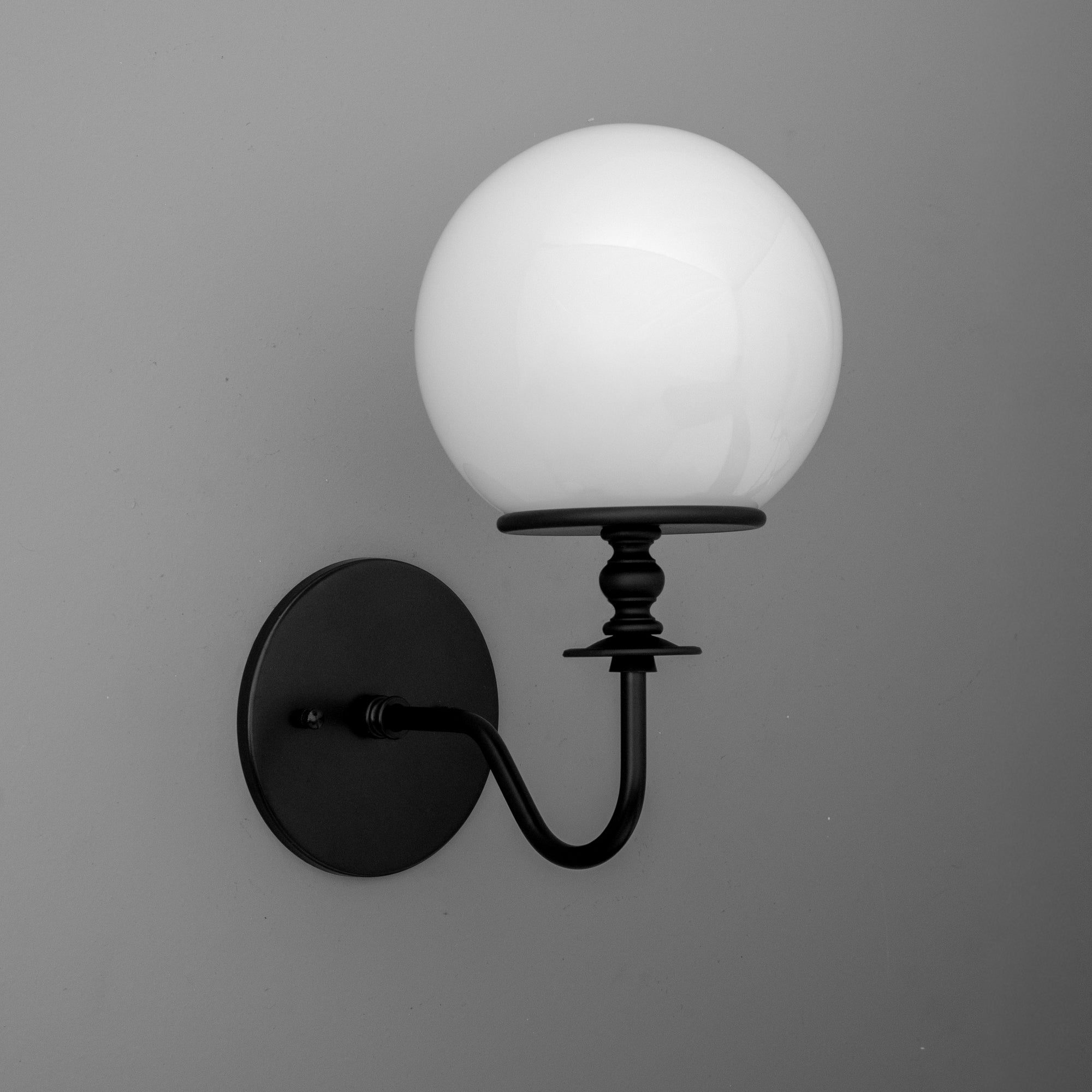 Wall-mounted black metal sconce with curved arm and round white glass globe shade. - SCONCE MODEL NO. 7857