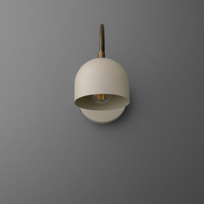 Matte white semi-flush wall sconce with dome-shaped shade and brass arm on gray wall. - SCONCE MODEL NO. 8586