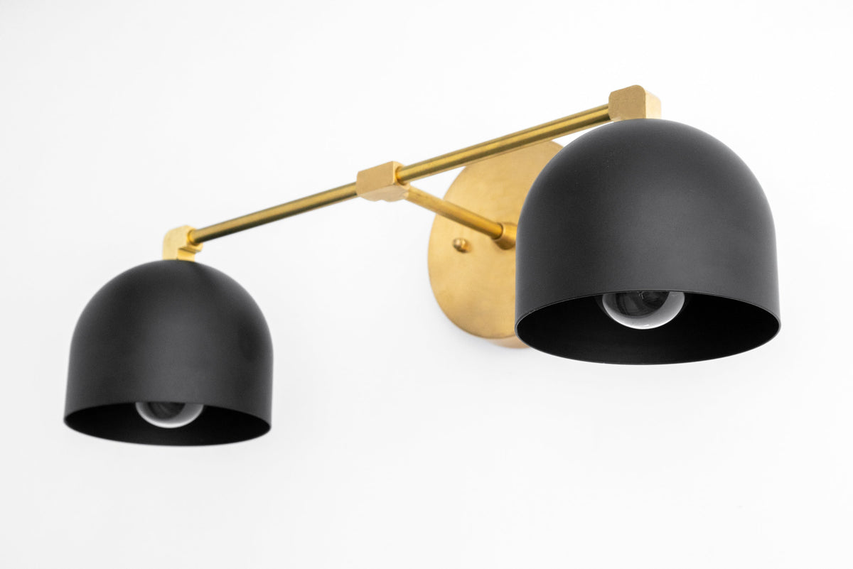 Mid-century modern vanity light with two black dome shades and antique brass mounting hardware. - VANITY LIGHT MODEL NO. 0698