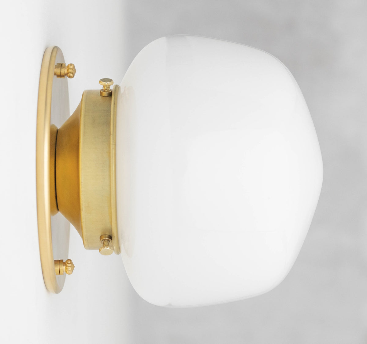 Wall sconce with an opal glass shade on a Raw or Sealed Brass fitter and round backplate, shown from the side. - SCONCE MODEL NO. 0746