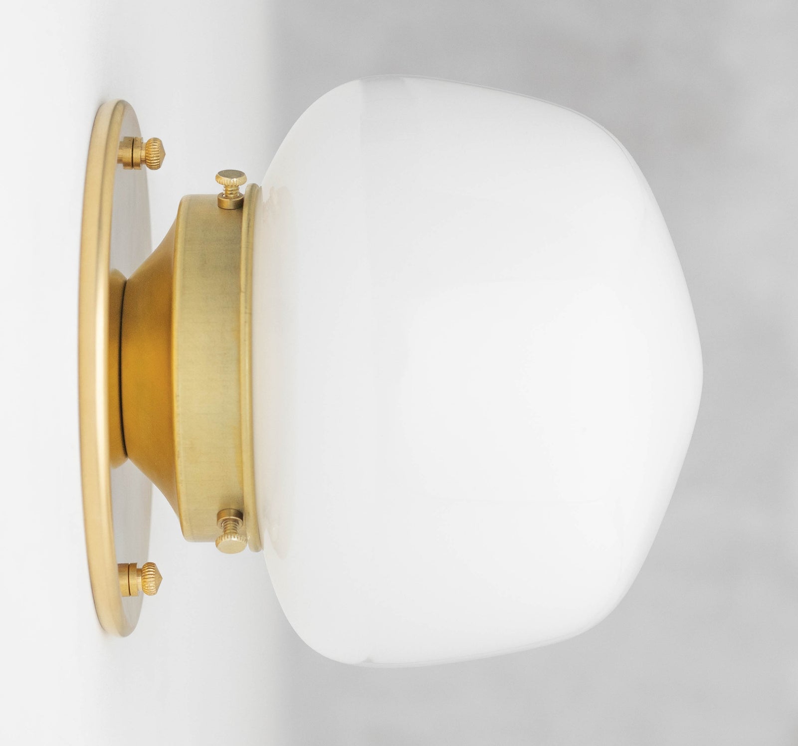 Wall sconce with an opal glass shade on a Raw or Sealed Brass fitter and round backplate, shown from the side. - SCONCE MODEL NO. 0746