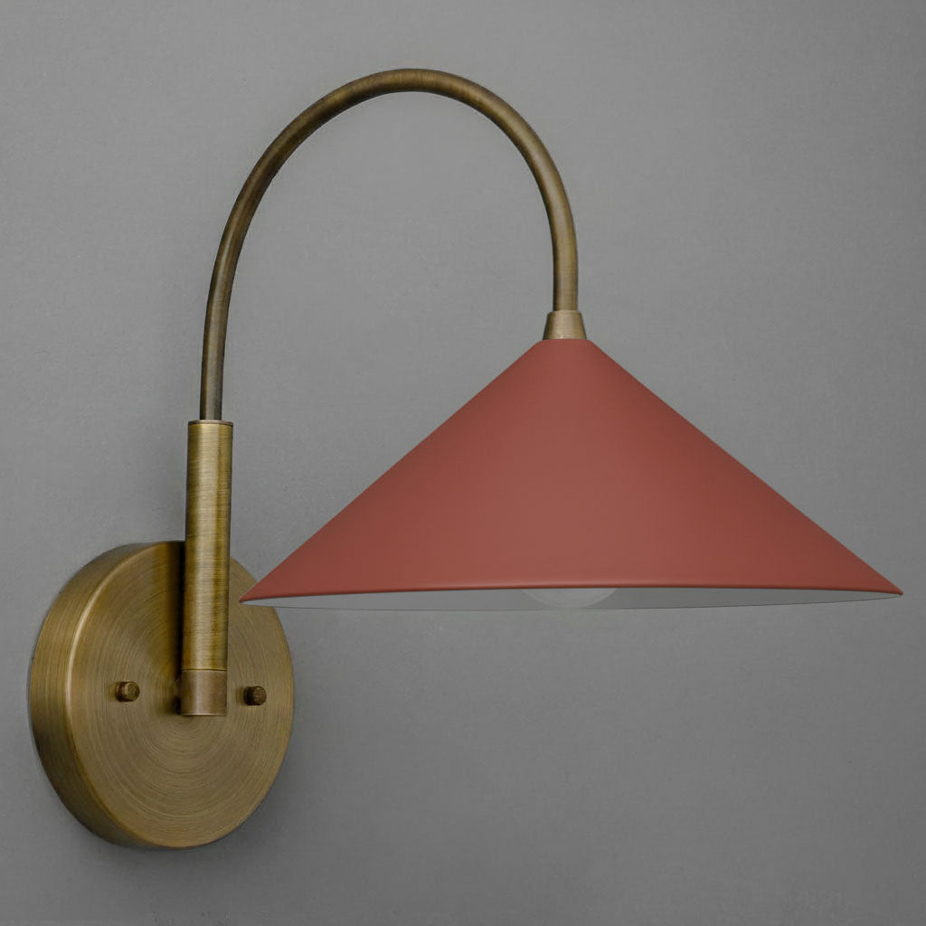 Antique brass wall sconce with a conical brick red shade and curved arm against gray background. - Sconce Model No. 1583