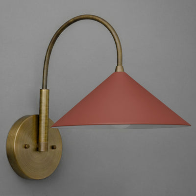 Antique brass wall sconce with a conical brick red shade and curved arm against gray background. - Sconce Model No. 1583