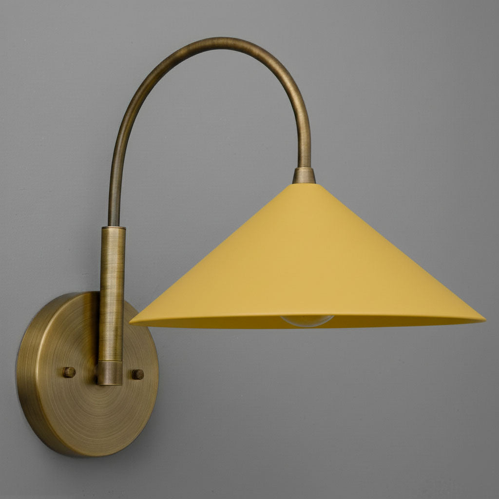 Antique brass sconce with curved arm and yellow conical lampshade against gray background. - Sconce Model No. 1583