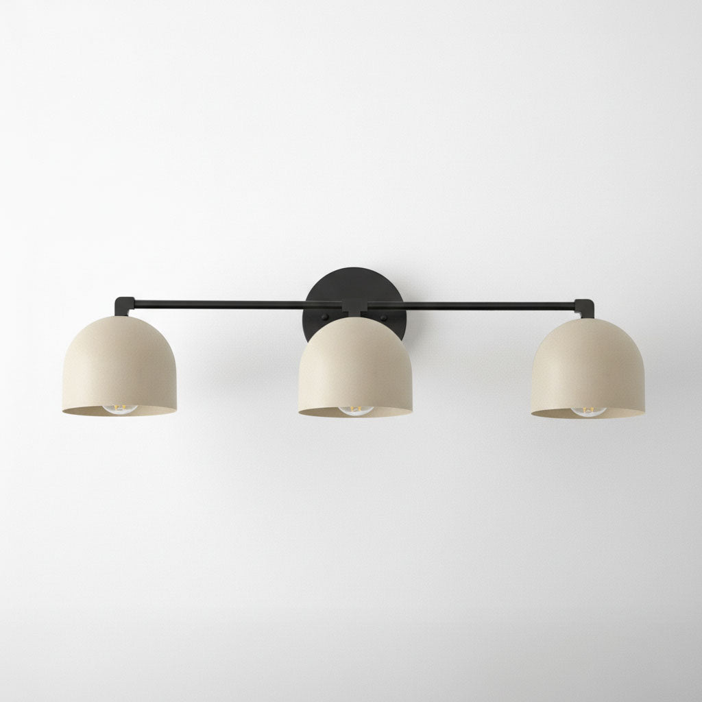 Three-bulb vanity light with black metal frame and cream curved shades against white background. - VANITY LIGHT MODEL NO. 7565