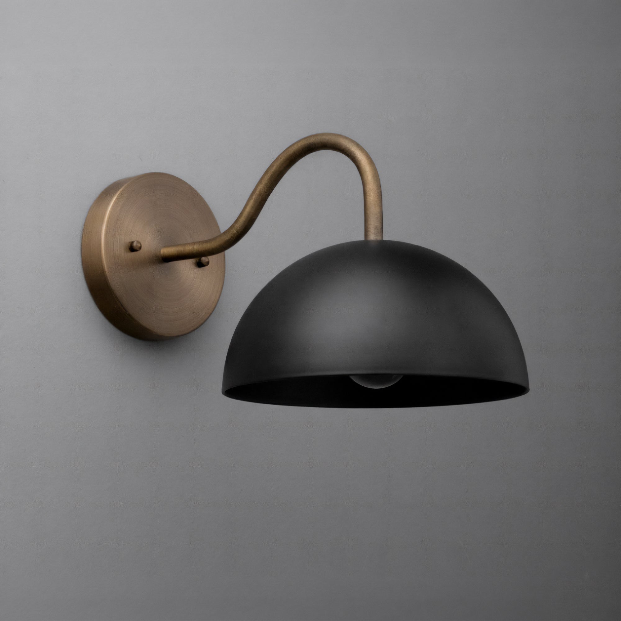 Wall sconce with matte black dome shade and curved bronze arm mounted on round bronze base. - SCONCE MODEL NO. 6678