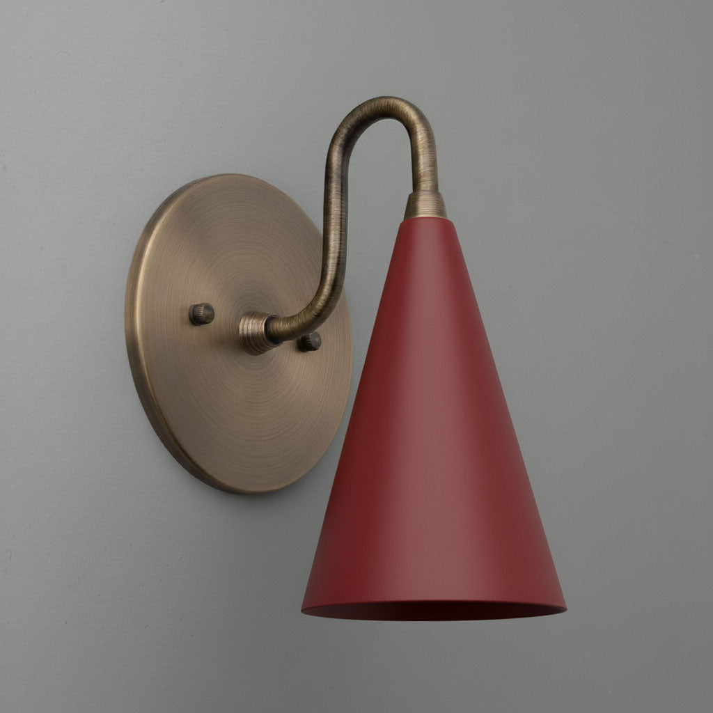Antique brass wall sconce with brick red conical shade against gray wall. - Sconce Model No. 2900
