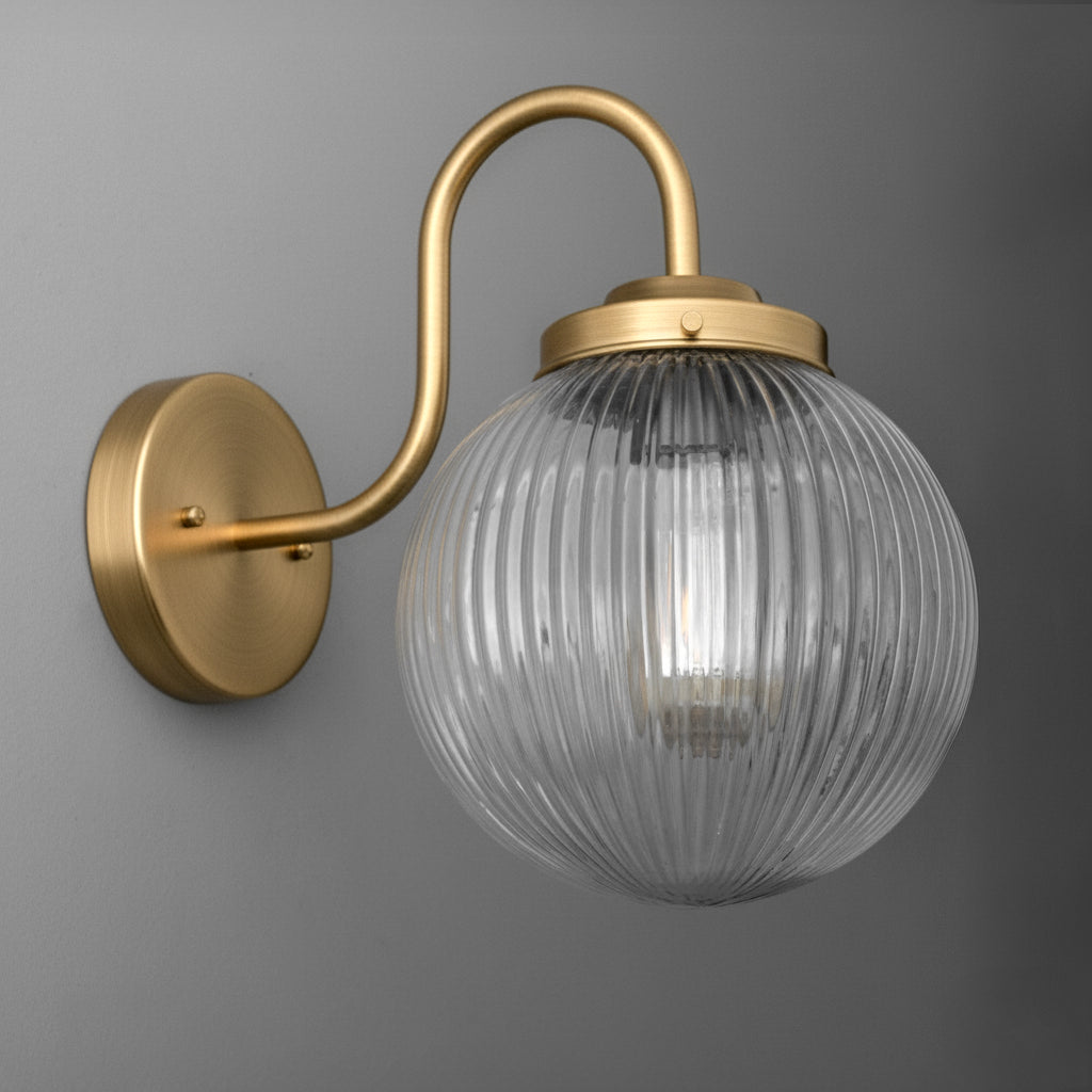 Wall-mounted gold metal sconce with ribbed clear glass globe shade and single bulb inside. - SCONCE MODEL NO. 1009
