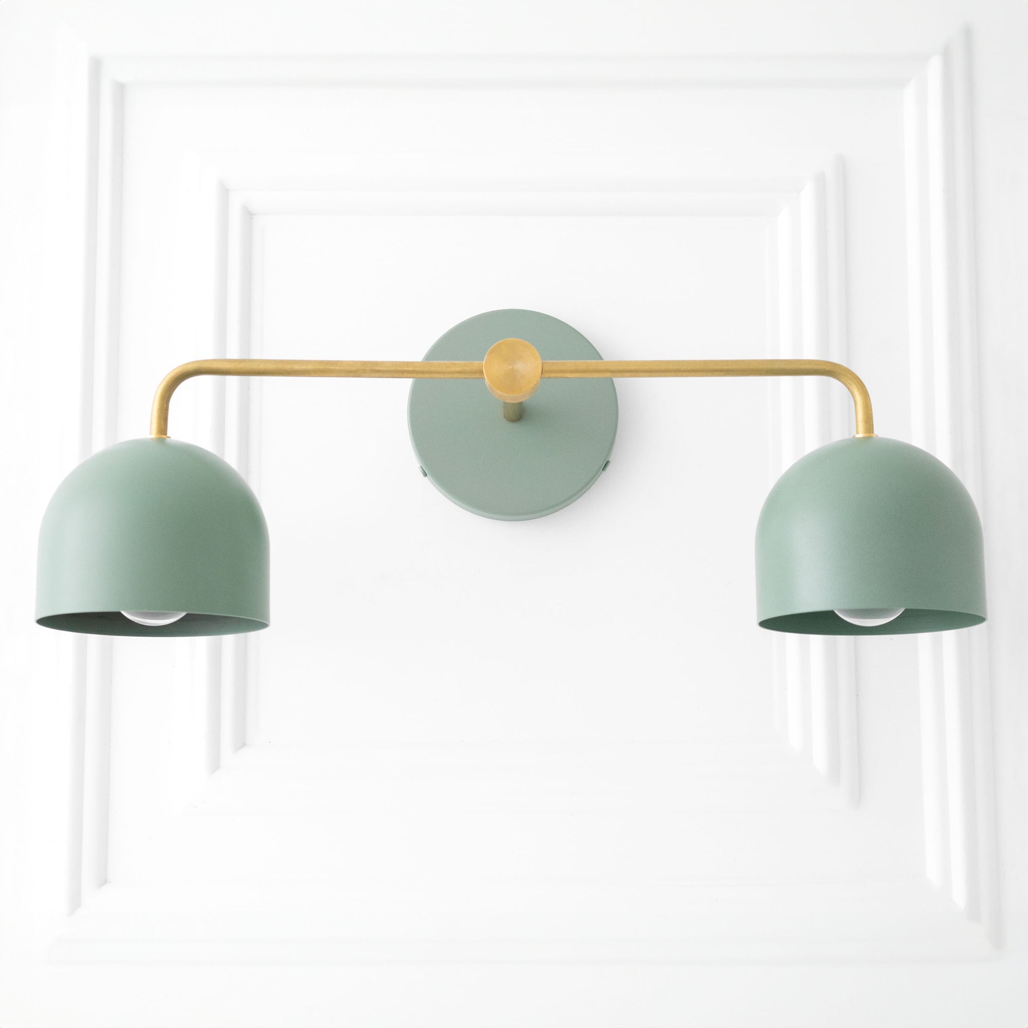 Two-bulb vanity light with matte green dome shades and brass horizontal arm mounted on round wall plate. - VANITY LIGHT MODEL NO. 2082