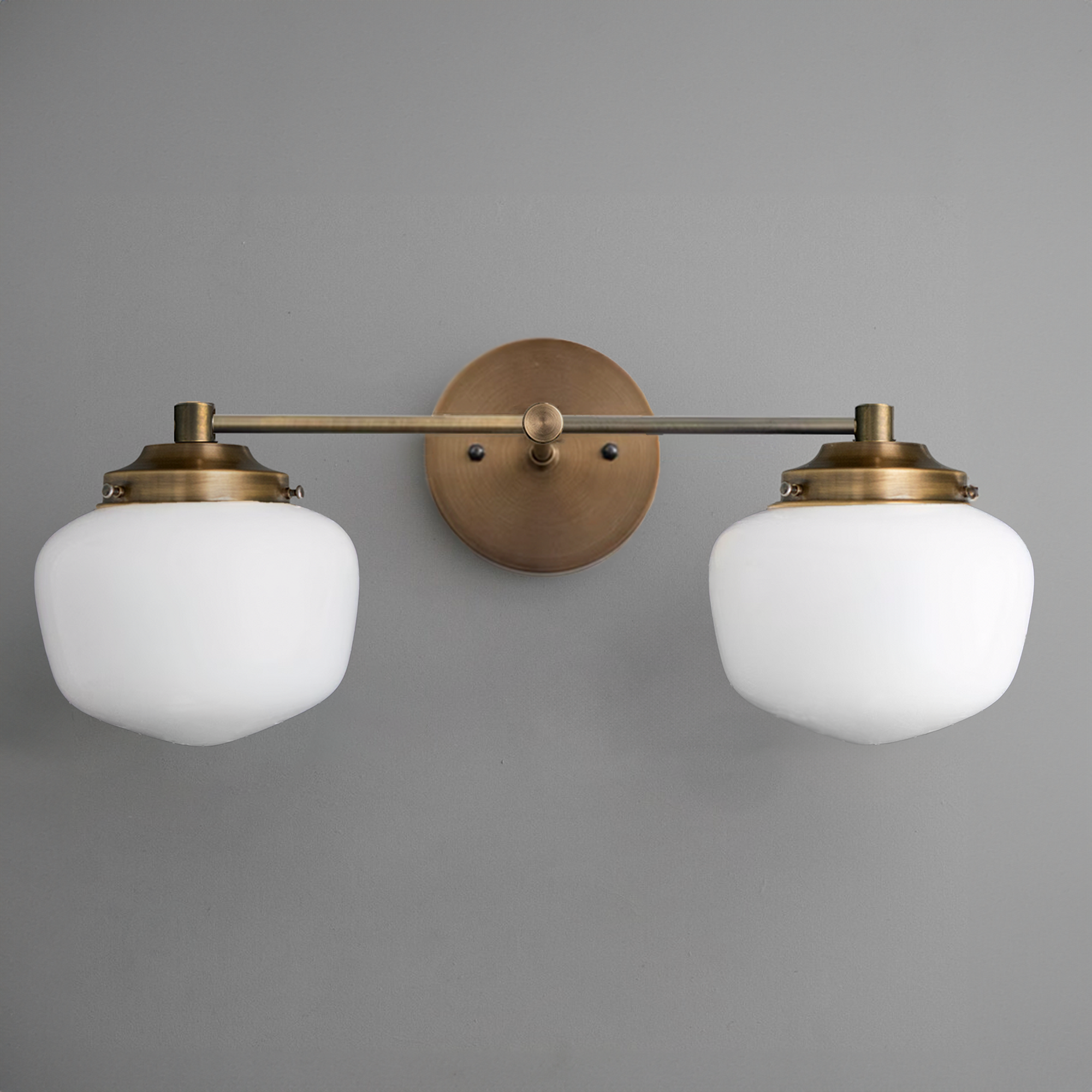 Art Deco 2-bulb vanity light with frosted globe shades and raw brass finish mounted on gray wall. - VANITY LIGHT MODEL NO. 5799