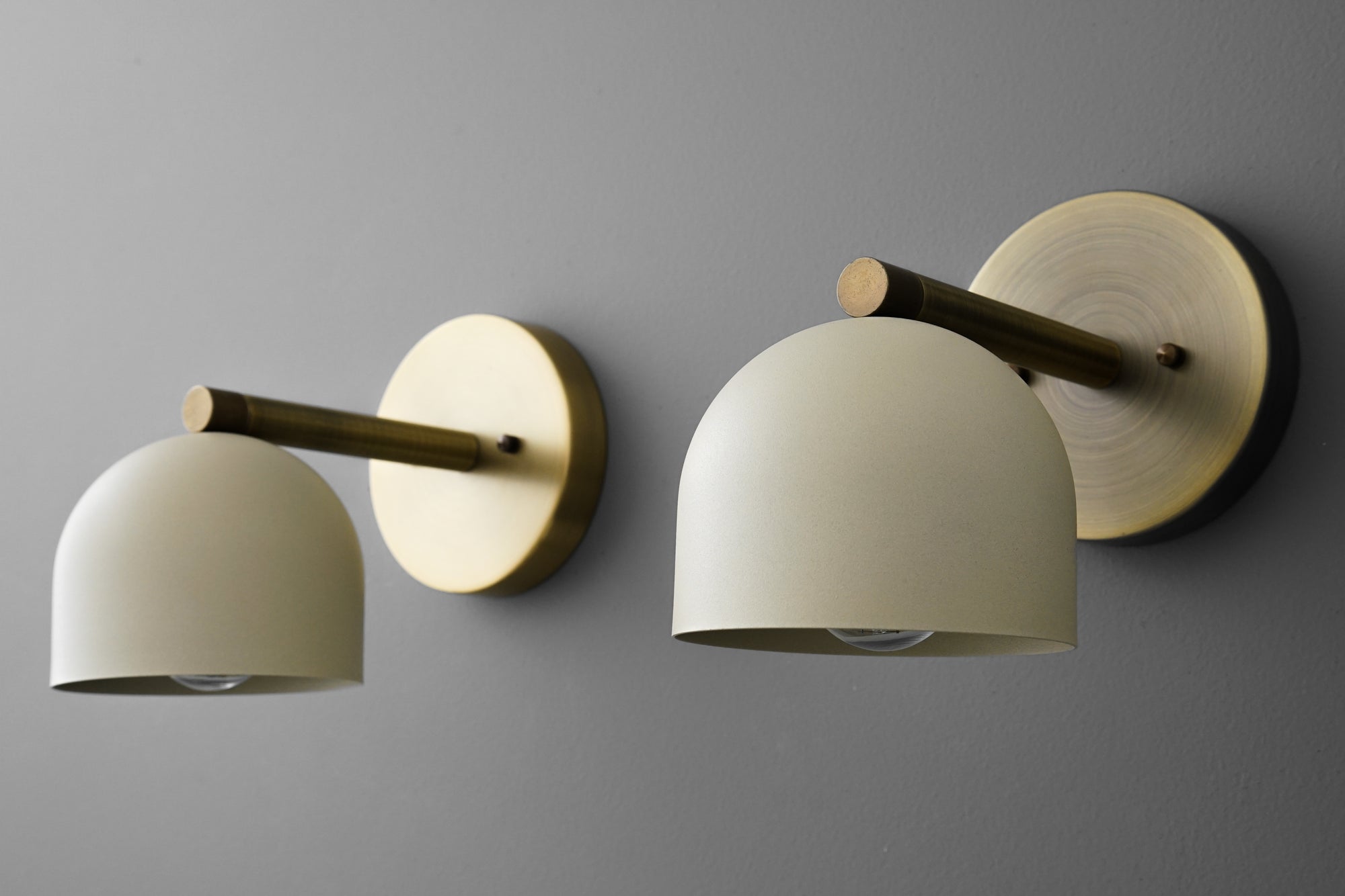 Antique brass wall sconce with matte cream half-globe shade mounted on round backplate with horizontal arm. - Sconce Model No. 5356