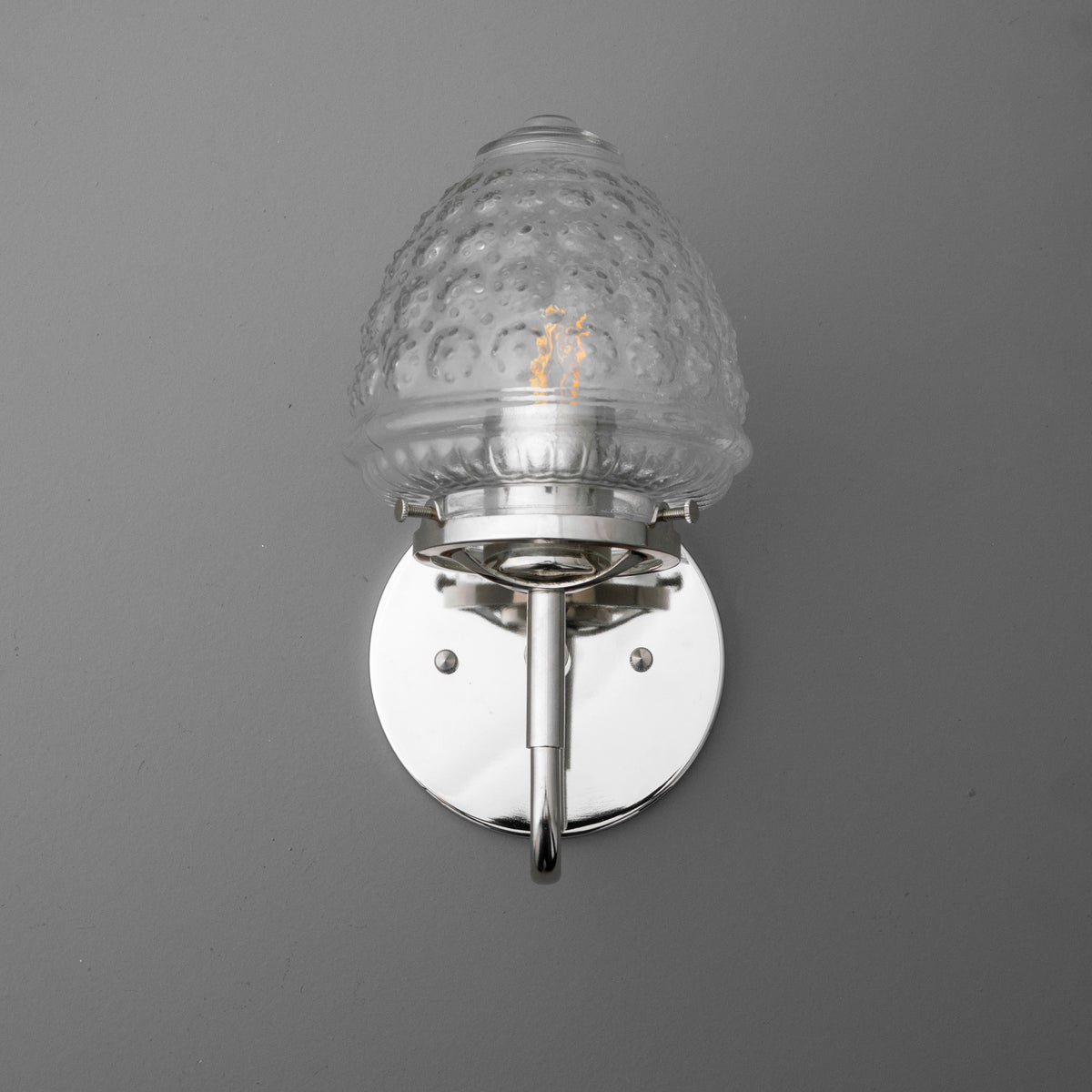 Wall-mounted sconce with clear textured glass shade and polished silver metal base. - SCONCE MODEL NO. 1037