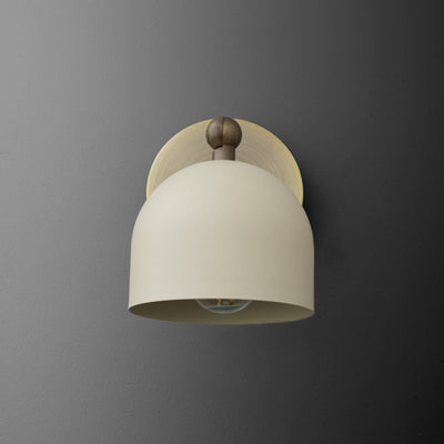Antique brass wall sconce with cream-colored cylinder shade and round backplate on gray wall. - SCONCE MODEL NO. 5103
