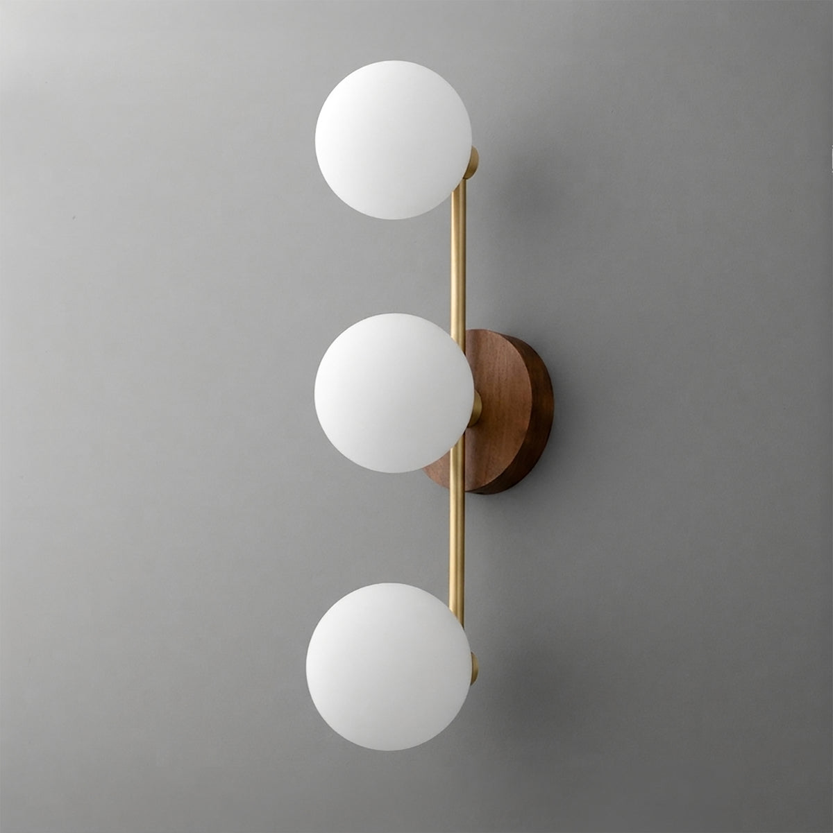 Modern wall sconce with three white frosted glass globes, brushed brass rod, and round wooden base. - SCONCE MODEL NO. 6089