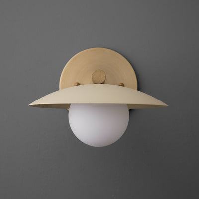 Minimalist wall sconce with antique brass finish and cream wide metal shade over white globe bulb. - SCONCE MODEL NO. 9875