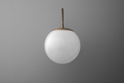 Round white glass globe sconce with antique brass metal mounting and arm on gray background. - SCONCE MODEL NO. 2947