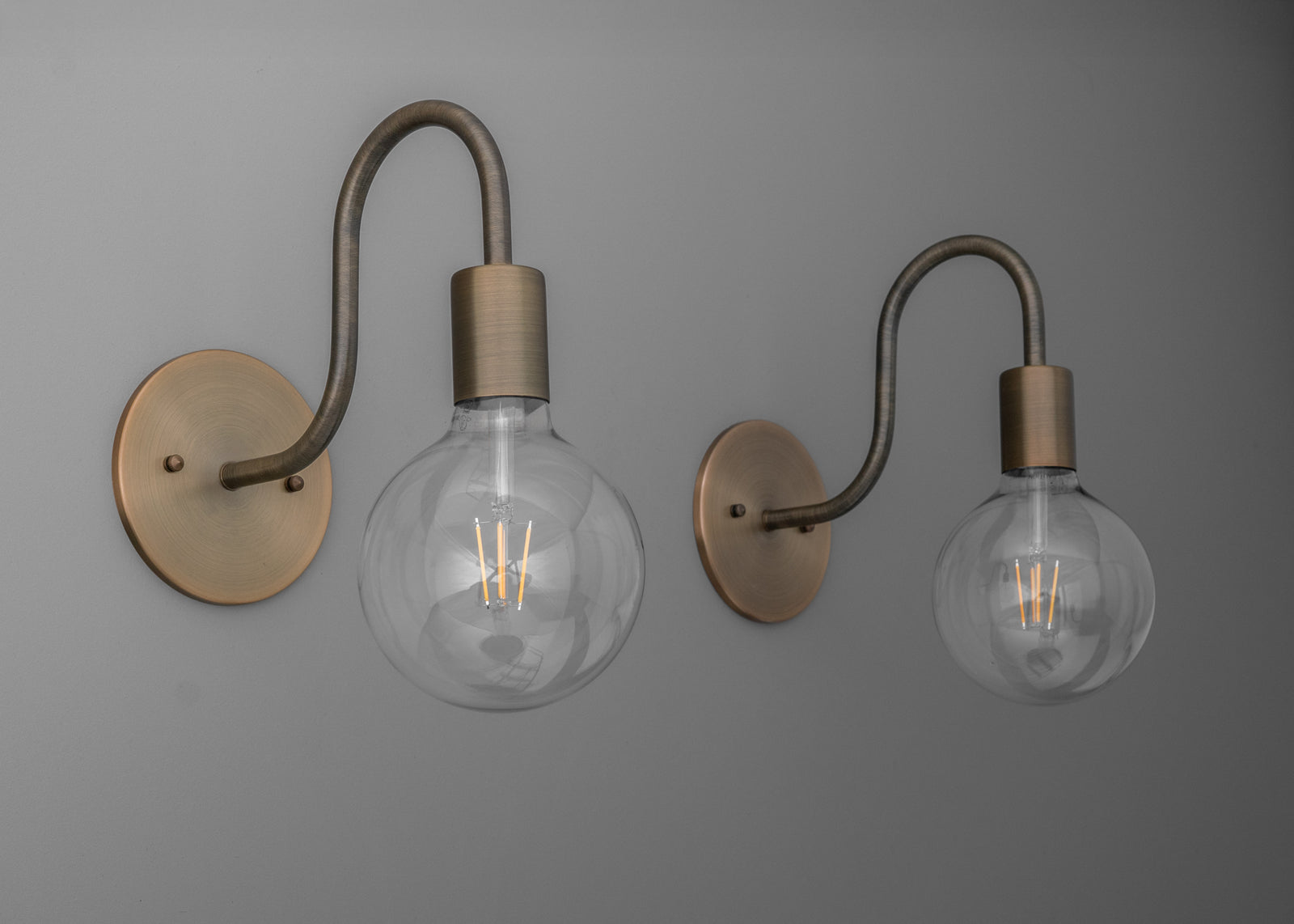 Pair of wall sconces with matte brass finish, curved arms, and exposed round filament bulbs. - SCONCE MODEL NO. 4753