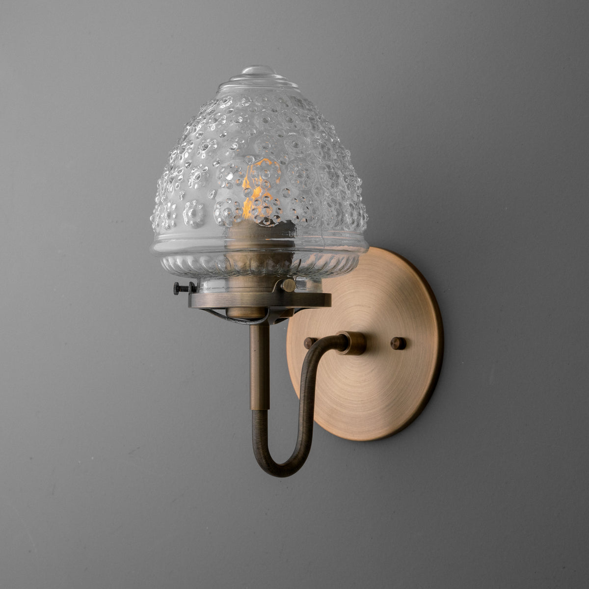 Antique brass wall sconce with clear textured glass shade and single bulb mount. - SCONCE MODEL NO. 1037